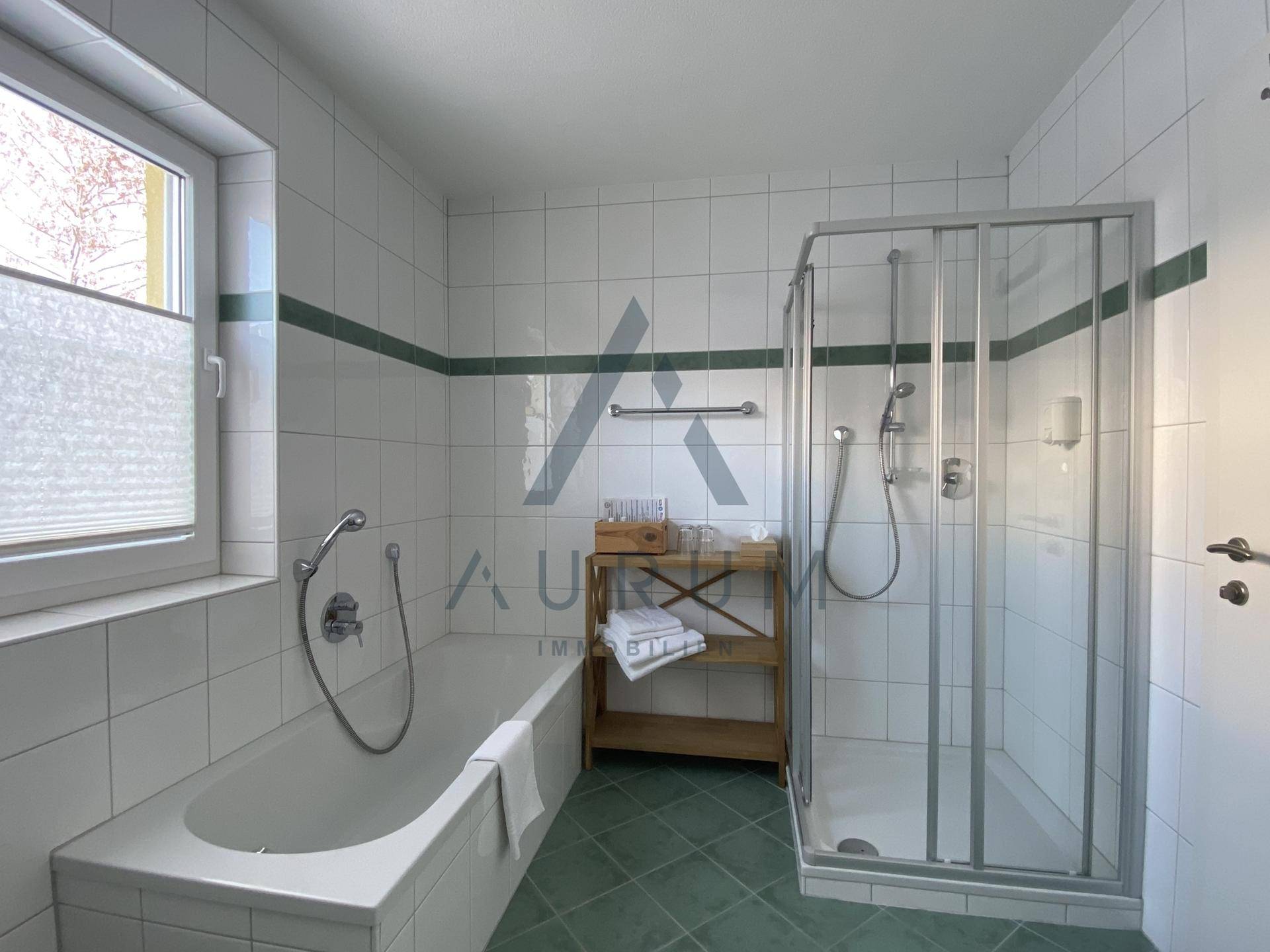 Helles Badezimmer mit Badewanne, Duschkabine und Fenster mit Blick auf die Berge.