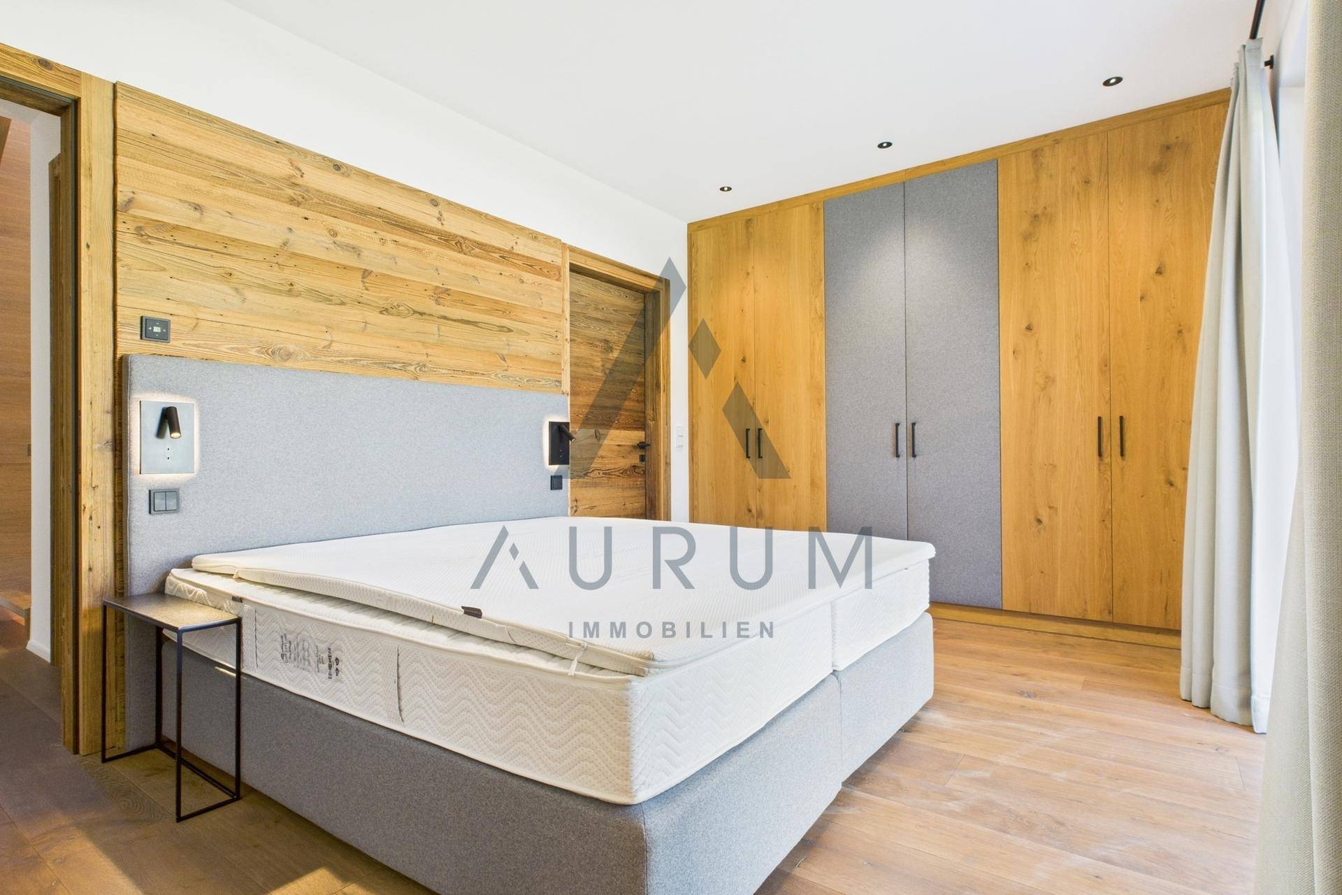 Gemütliches Schlafzimmer mit Holzwänden, Einbauschränken und modernem Doppelbett.