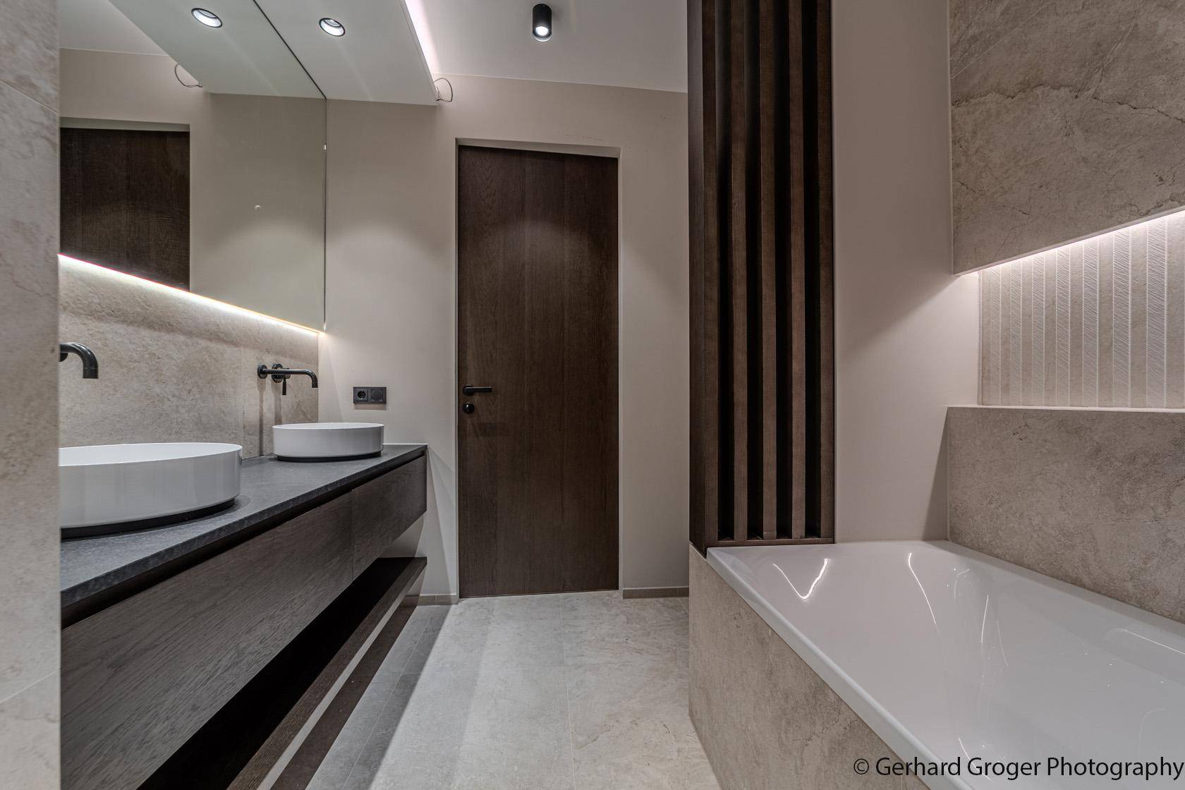Elegantes Badezimmer mit Badewanne, Doppelwaschbecken und indirekter Beleuchtung.
