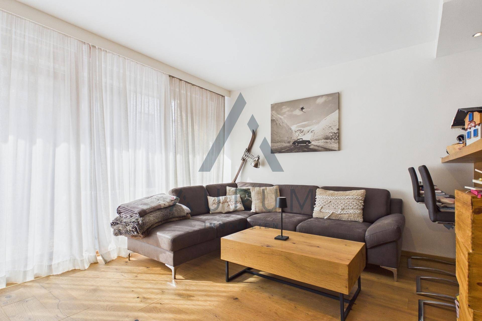 Helles Wohnzimmer mit großem Ecksofa, Holztisch und bodentiefen Fenstern für viel Tageslicht.