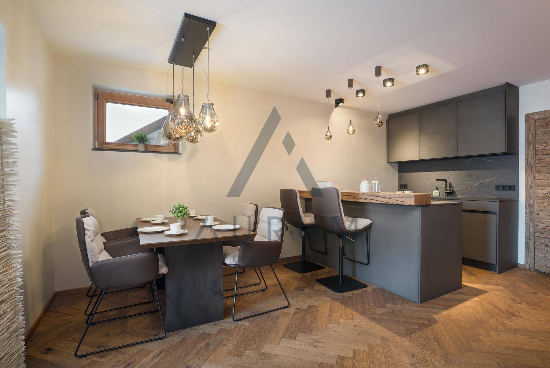 Kompakte Küche mit Essbereich, Frühstücksbar und modernen Hängelampen in einem hellen Raum.
