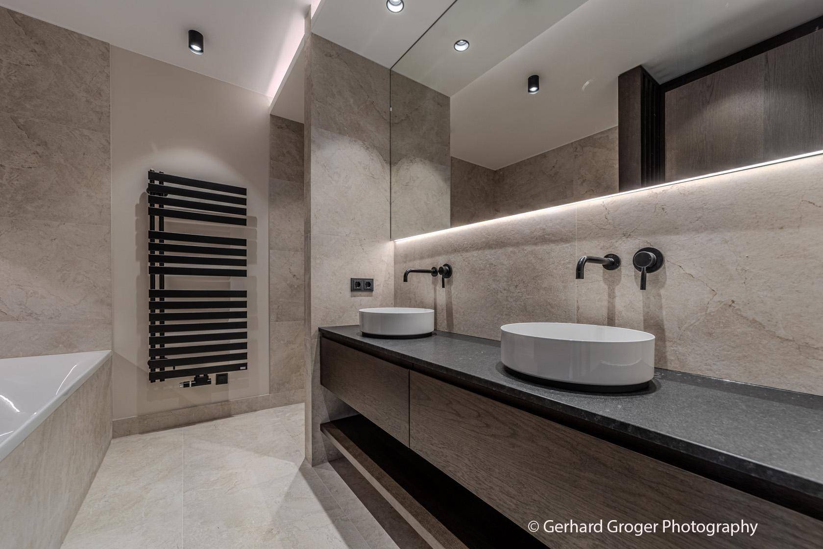 Luxuriöses Badezimmer mit Doppelwaschbecken, großem Spiegel und beheiztem Handtuchhalter.