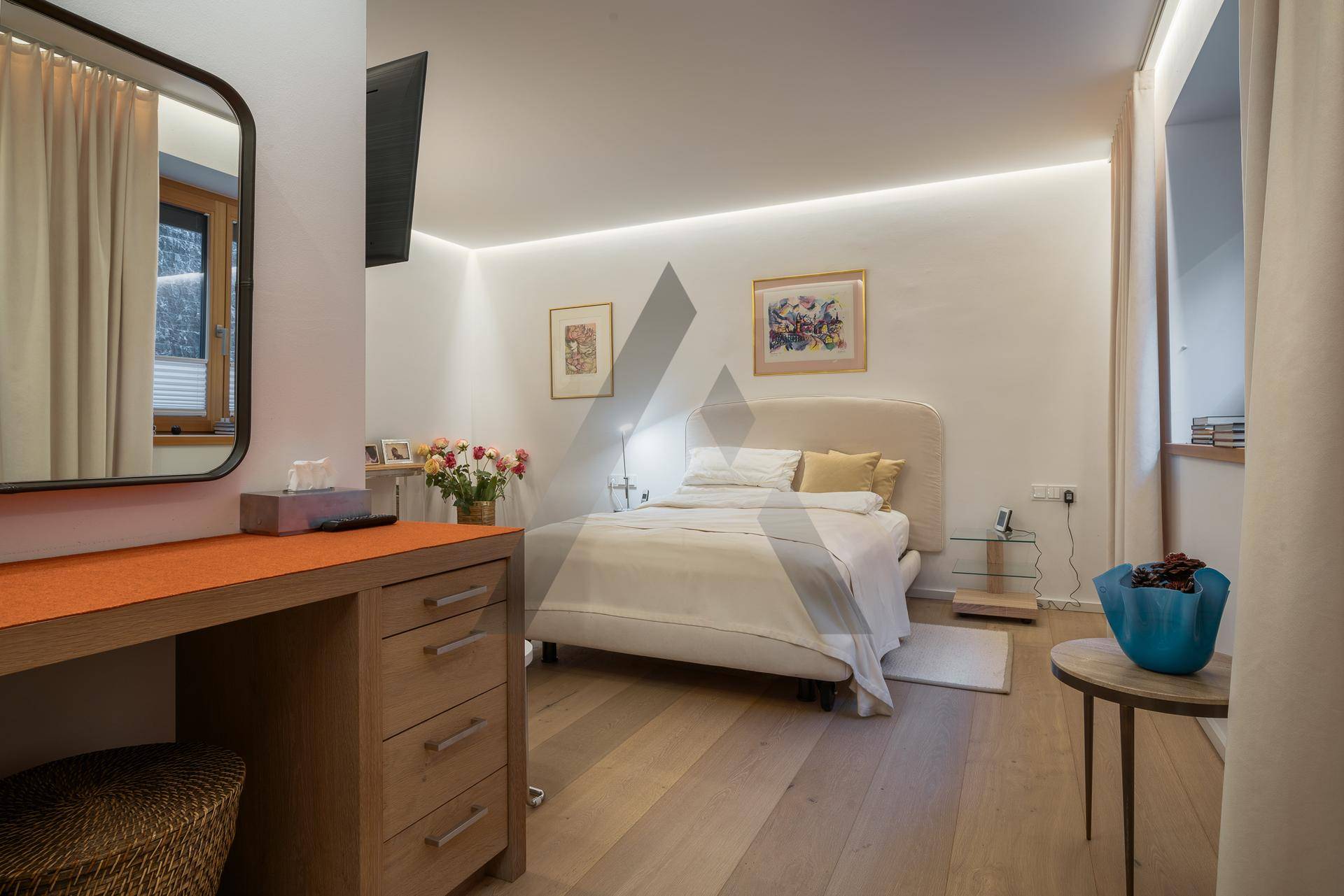 Gemütliches Schlafzimmer mit Doppelbett, Schminktisch und indirekter Beleuchtung für eine entspannte Atmosphäre.