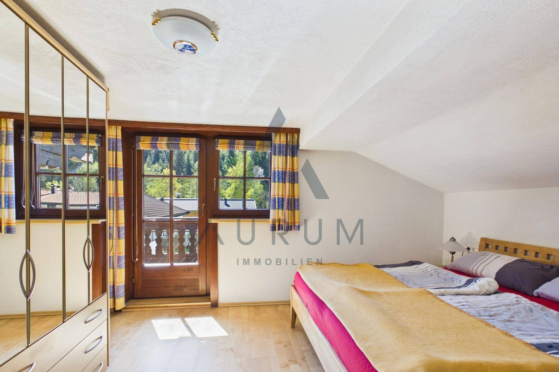 Schlafzimmer mit Holzbalkon-Zugang, Dachschräge und Blick ins Grüne.