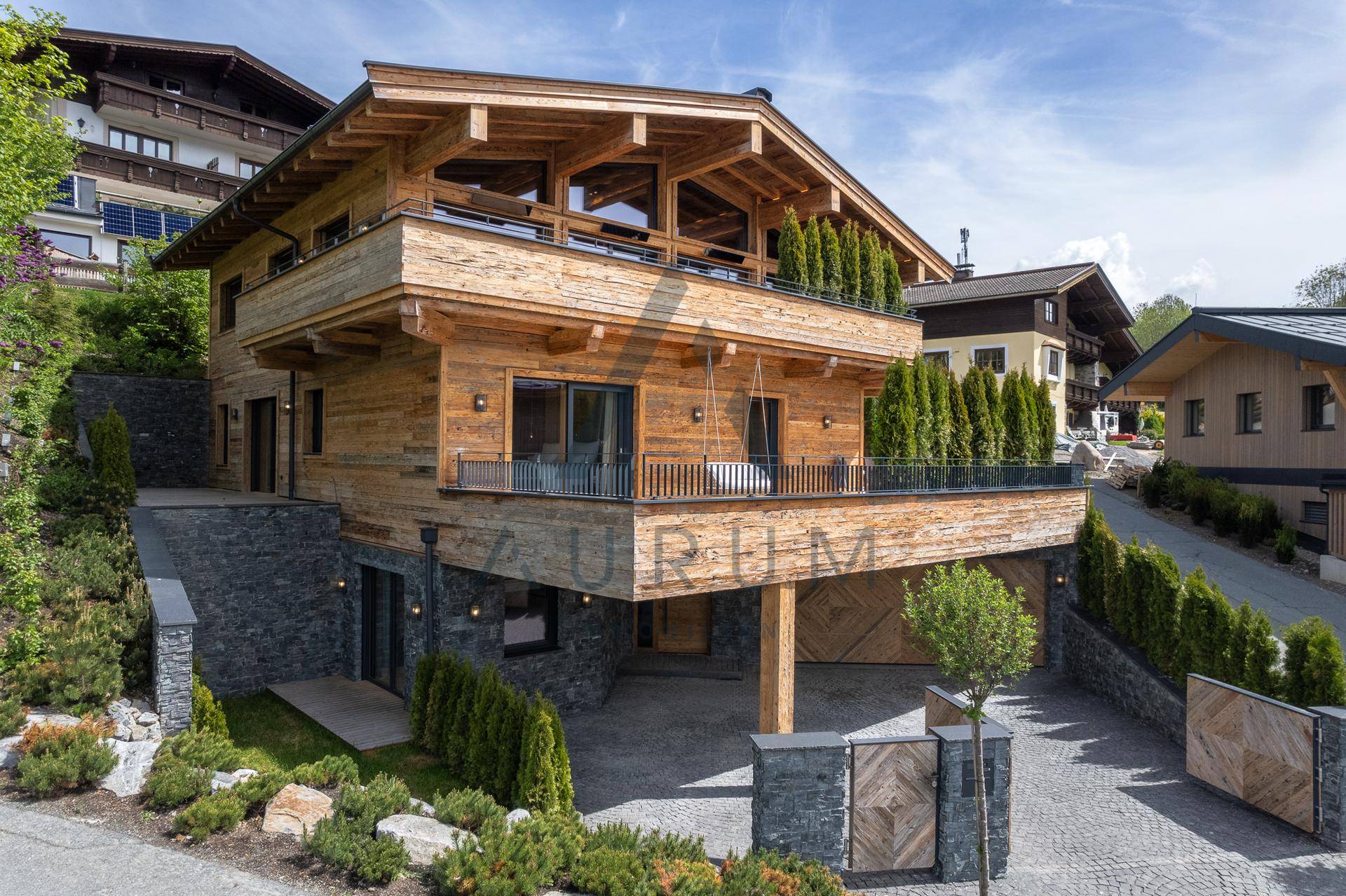 Beeindruckendes Chalet mit Holzfassade, Steinakzenten und mehreren Balkonen in alpiner Umgebung.