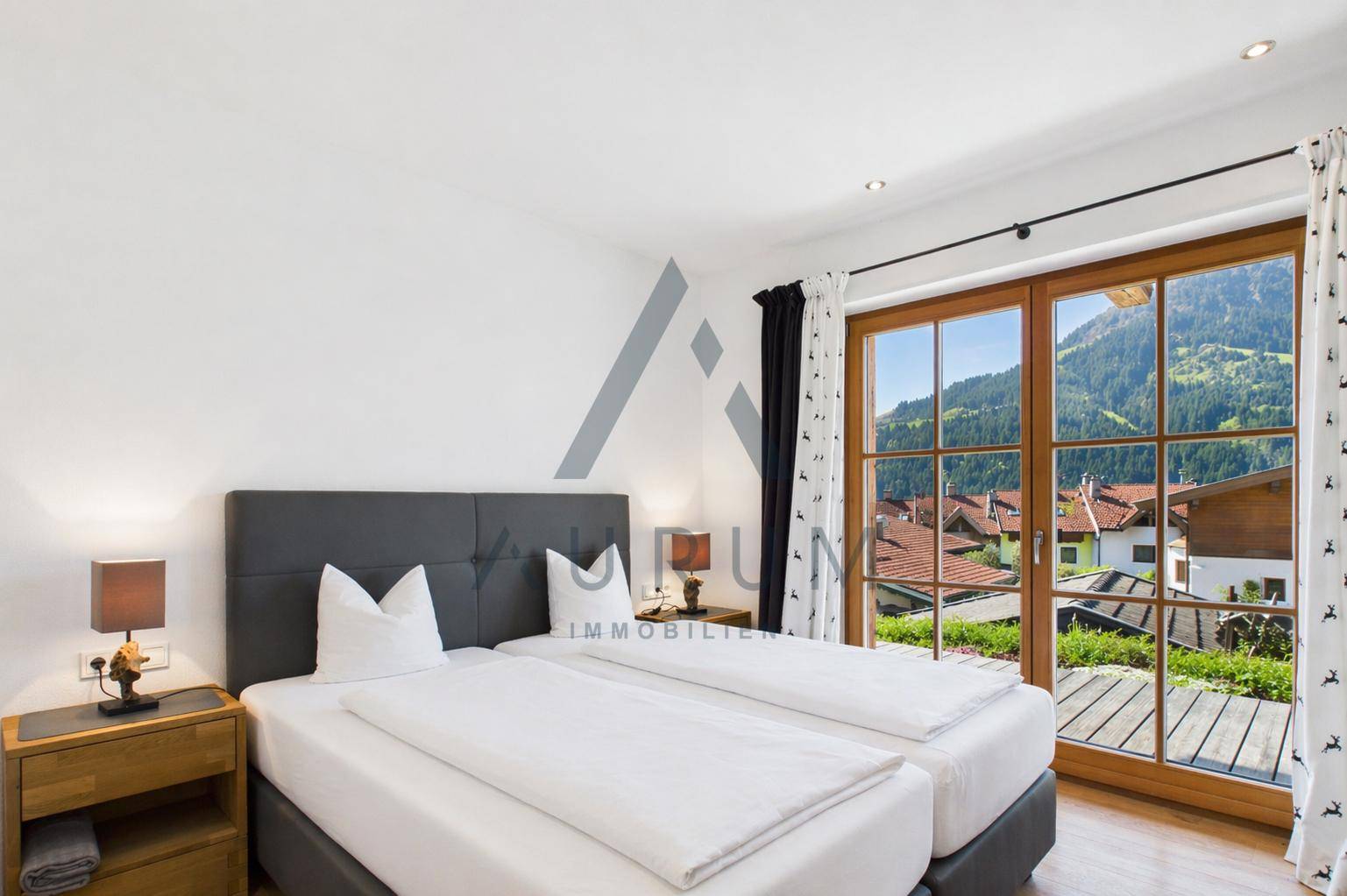 Helles Schlafzimmer mit zwei Einzelbetten und großer Fensterfront mit Blick ins Grüne.