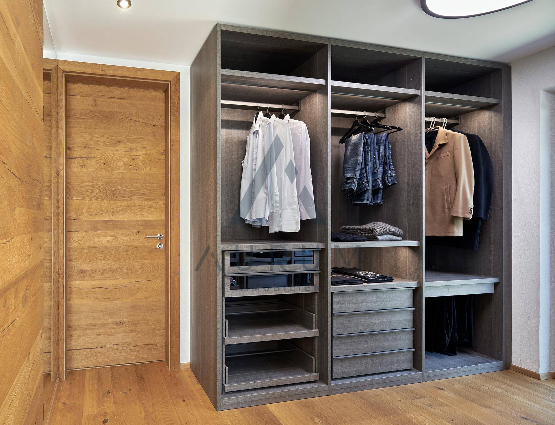 Geräumiger begehbarer Kleiderschrank mit integrierten Fächern und Hängemöglichkeiten, aus dunklem Holz.