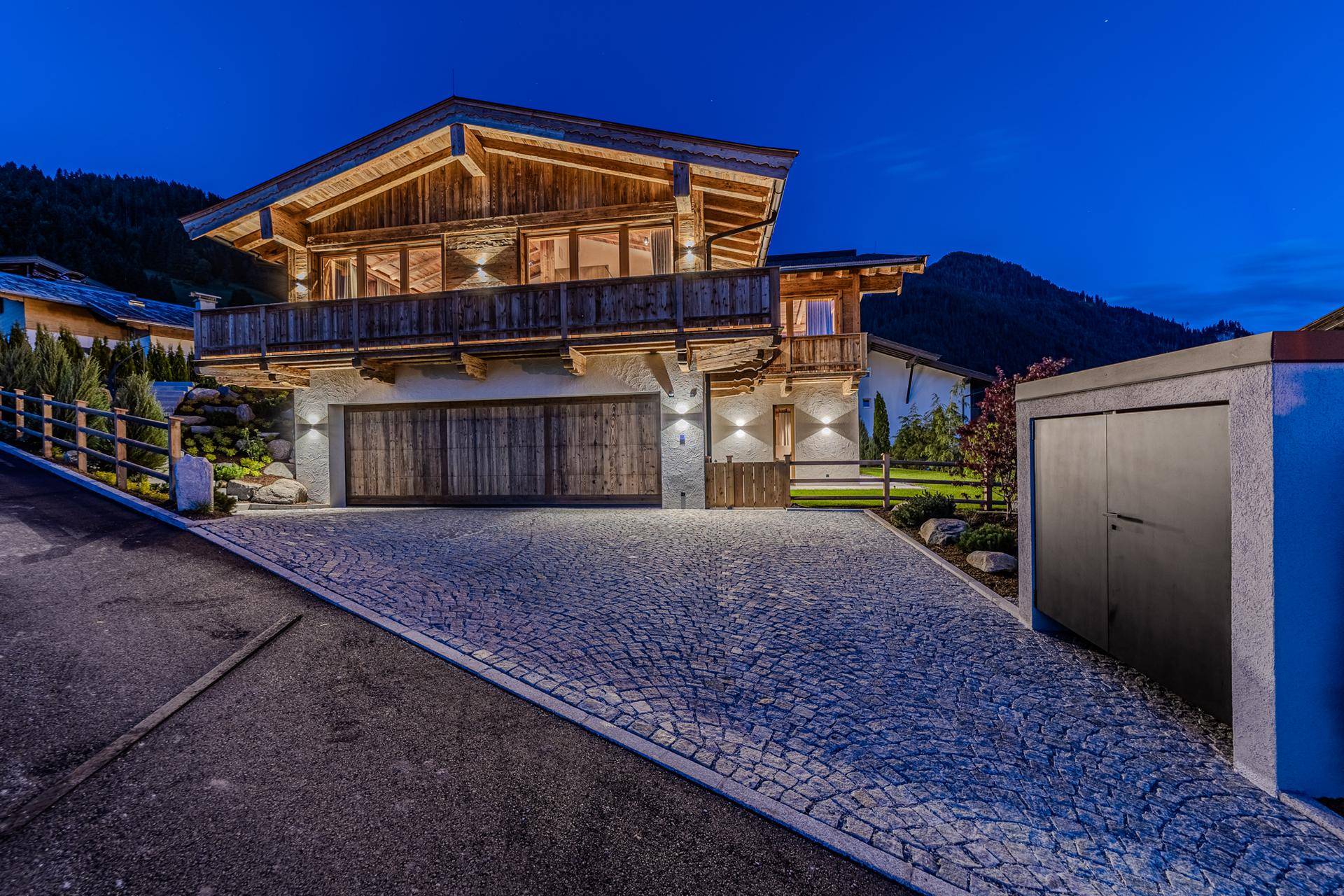 Elegante Chalet-Villa bei Nacht mit gepflasterter Auffahrt und integrierter Doppelgarage.