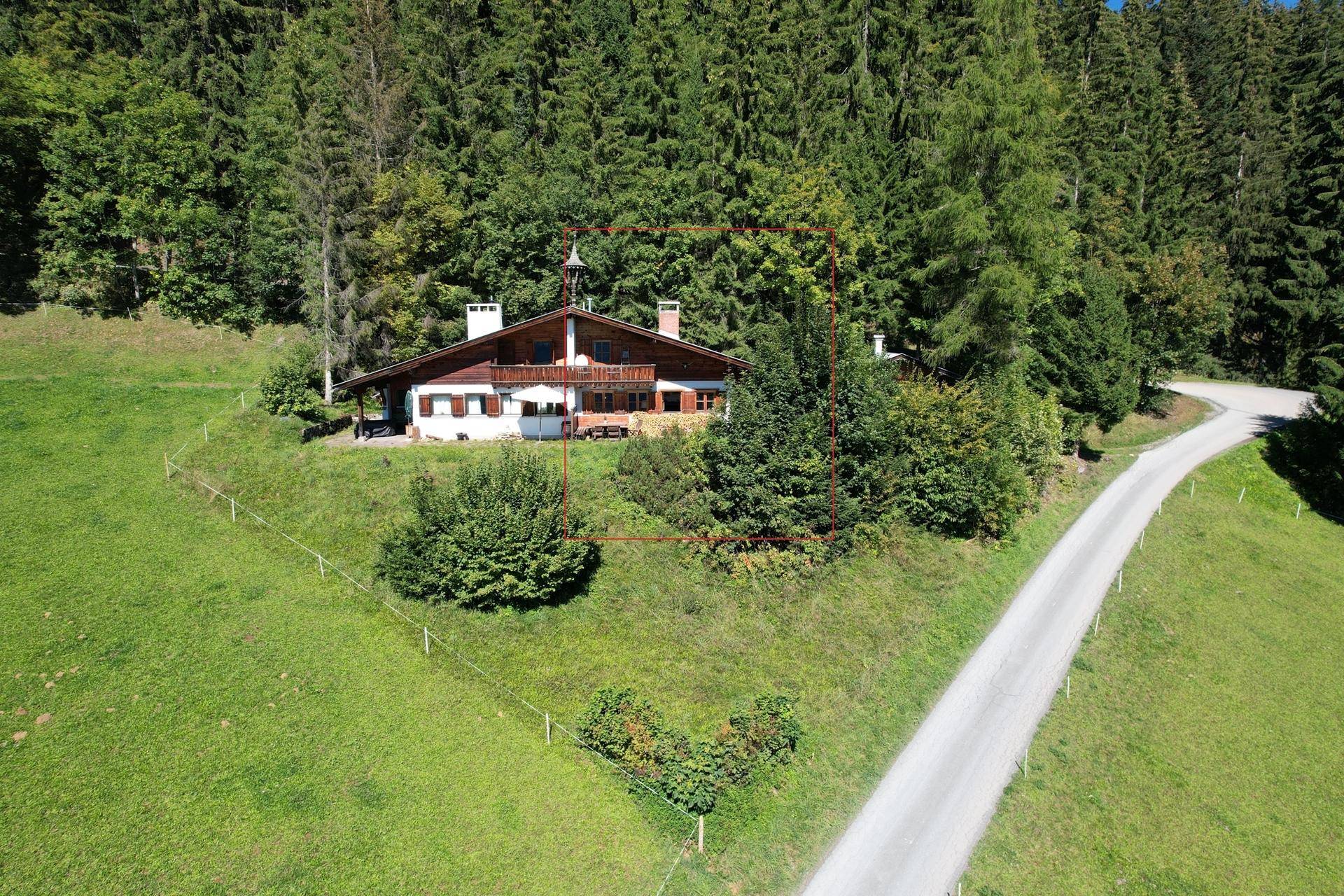 Luftaufnahme des Chalets in idyllischer Hanglage umgeben von Wald und Wiesen.