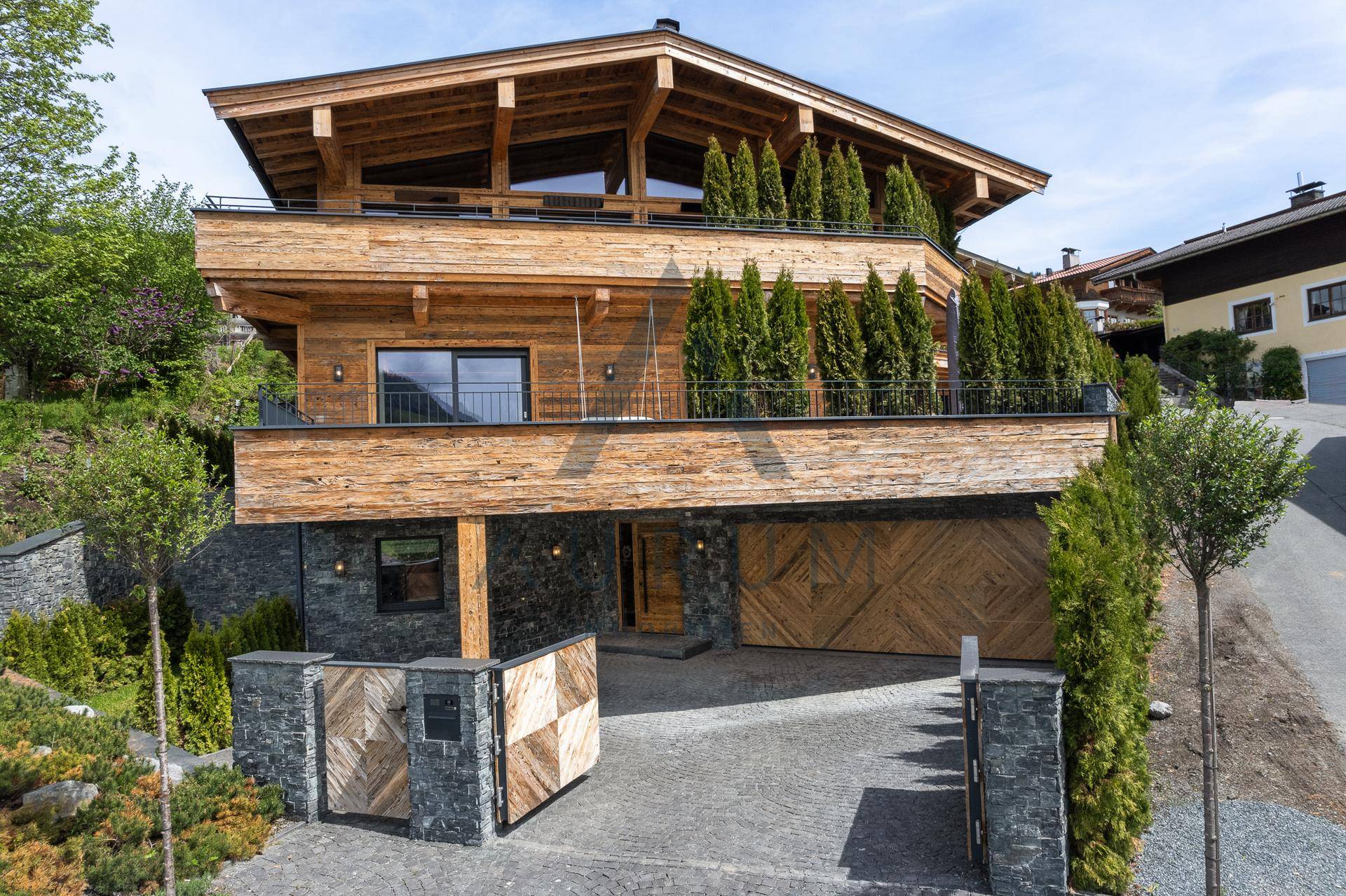 Luxuriöses Chalet mit traditioneller Holzfassade, modernen Steinakzenten und gepflegter Auffahrt.
