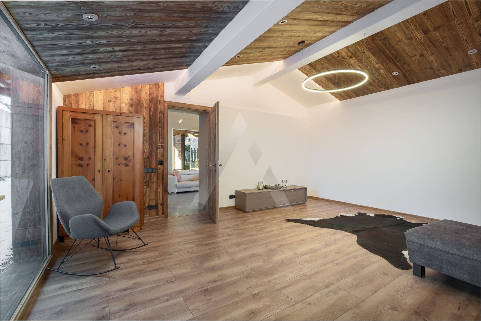 Helles Zimmer mit Holzboden, Holzwänden und moderner Beleuchtung.