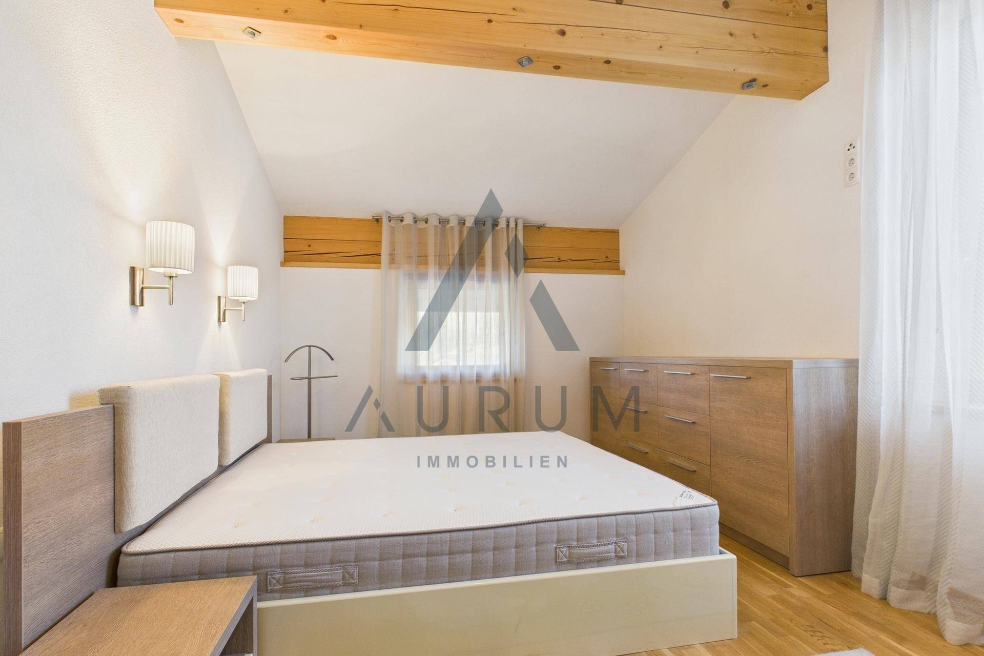 Gemütliches Schlafzimmer mit Holzboden, Doppelbett und sichtbaren Holzbalken an der Decke.