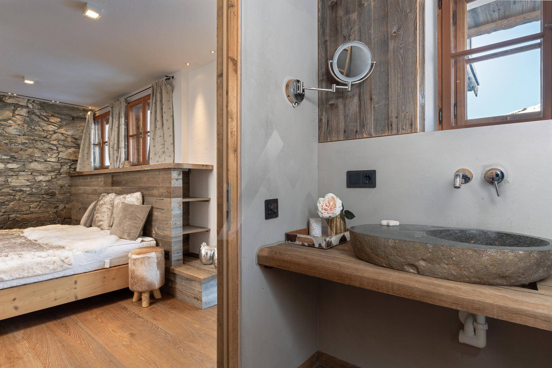 Ensuite-Badezimmer mit Steinwaschbecken und Holzelementen, direkt vom Schlafzimmer zugänglich.