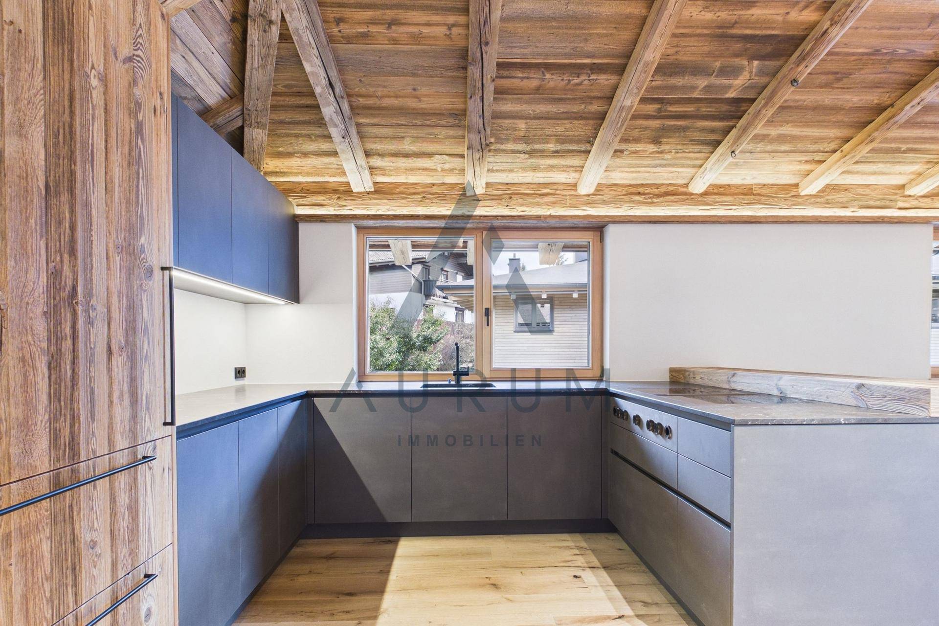 Geräumige U-förmige Küche mit Holzbalkendecke, modernen Schränken, Arbeitsflächen und Fenster.