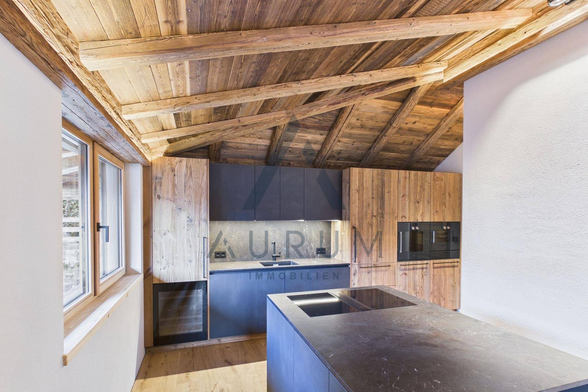 Moderne Küche mit Holzbalkendecke, Kücheninsel, integrierten Geräten und Weinkühler in einem Dachgeschoss.