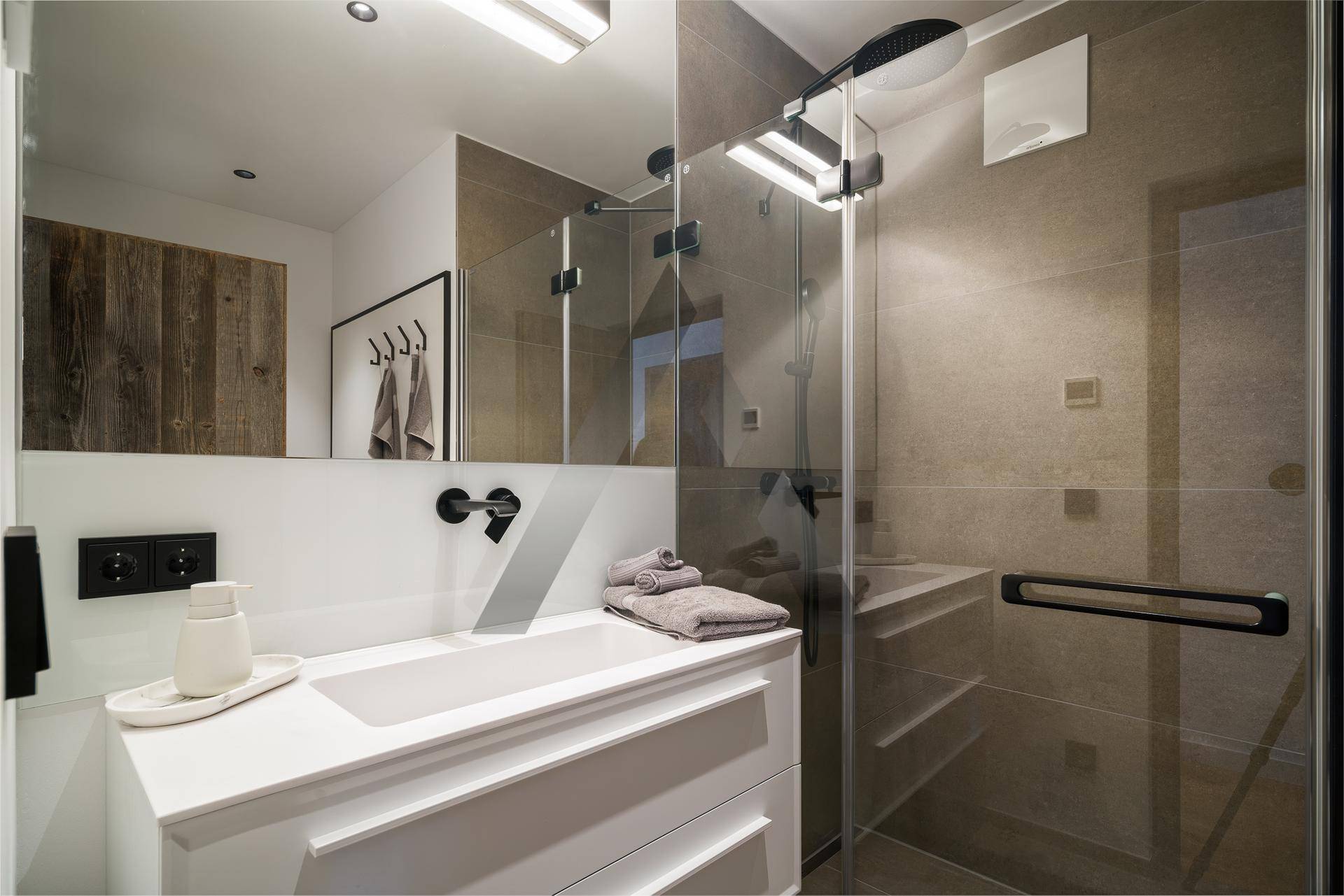 Modernes Badezimmer mit begehbarer Dusche, großformatigen Fliesen und Einzelwaschbecken.