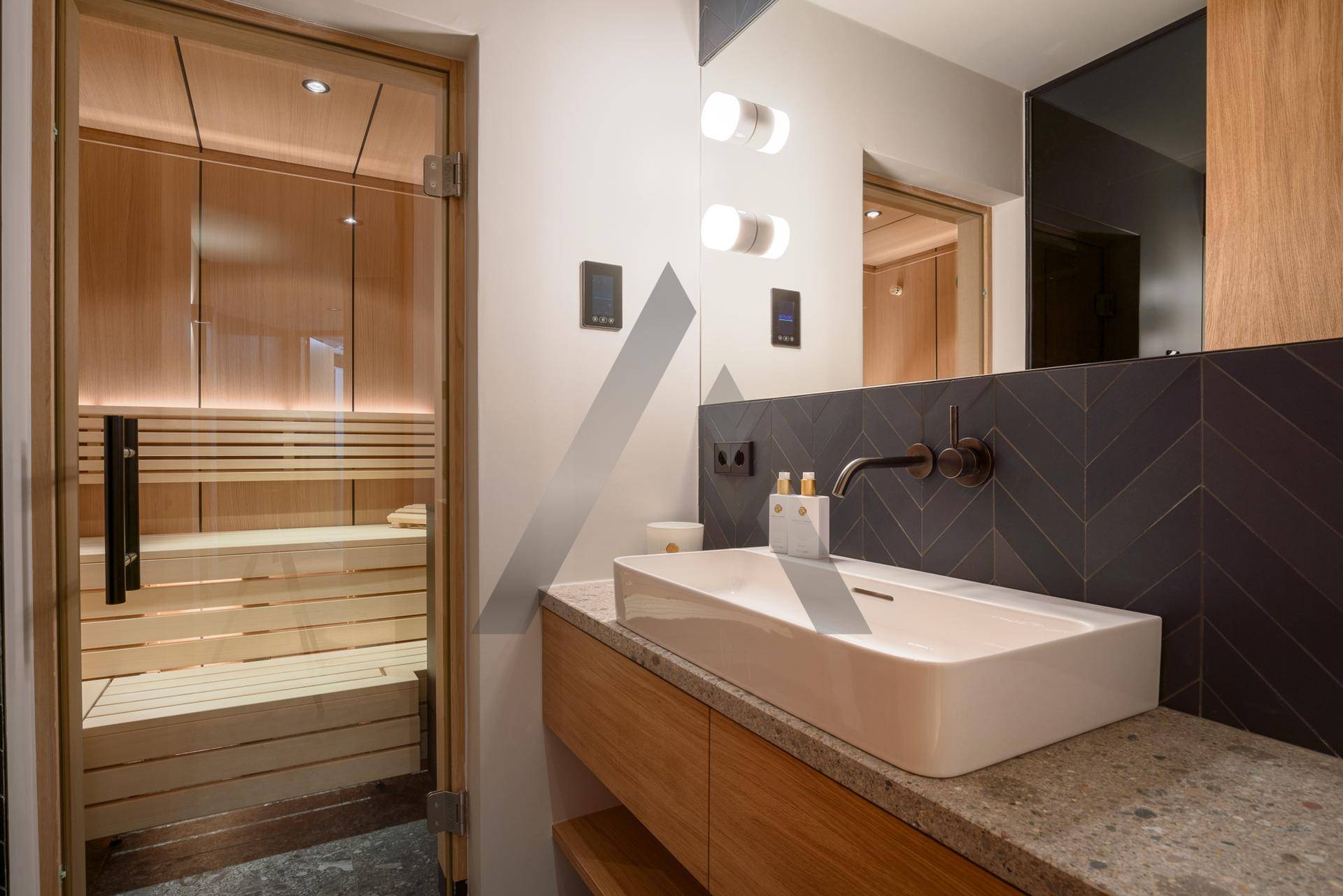 Badezimmer mit Waschbecken und integrierter Sauna für entspannende Wellnessmomente.