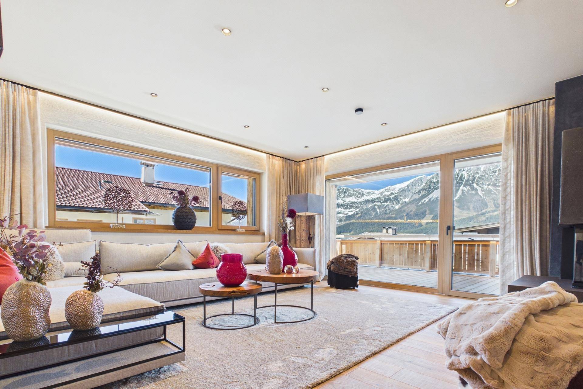 Helles Wohnzimmer mit großzügiger Couch, Holzboden und beeindruckendem Bergblick.
