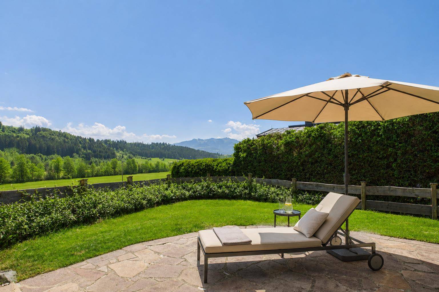 Gepflegter Gartenbereich mit Liegewiese, Liegestuhl und weitem Blick in die Landschaft.