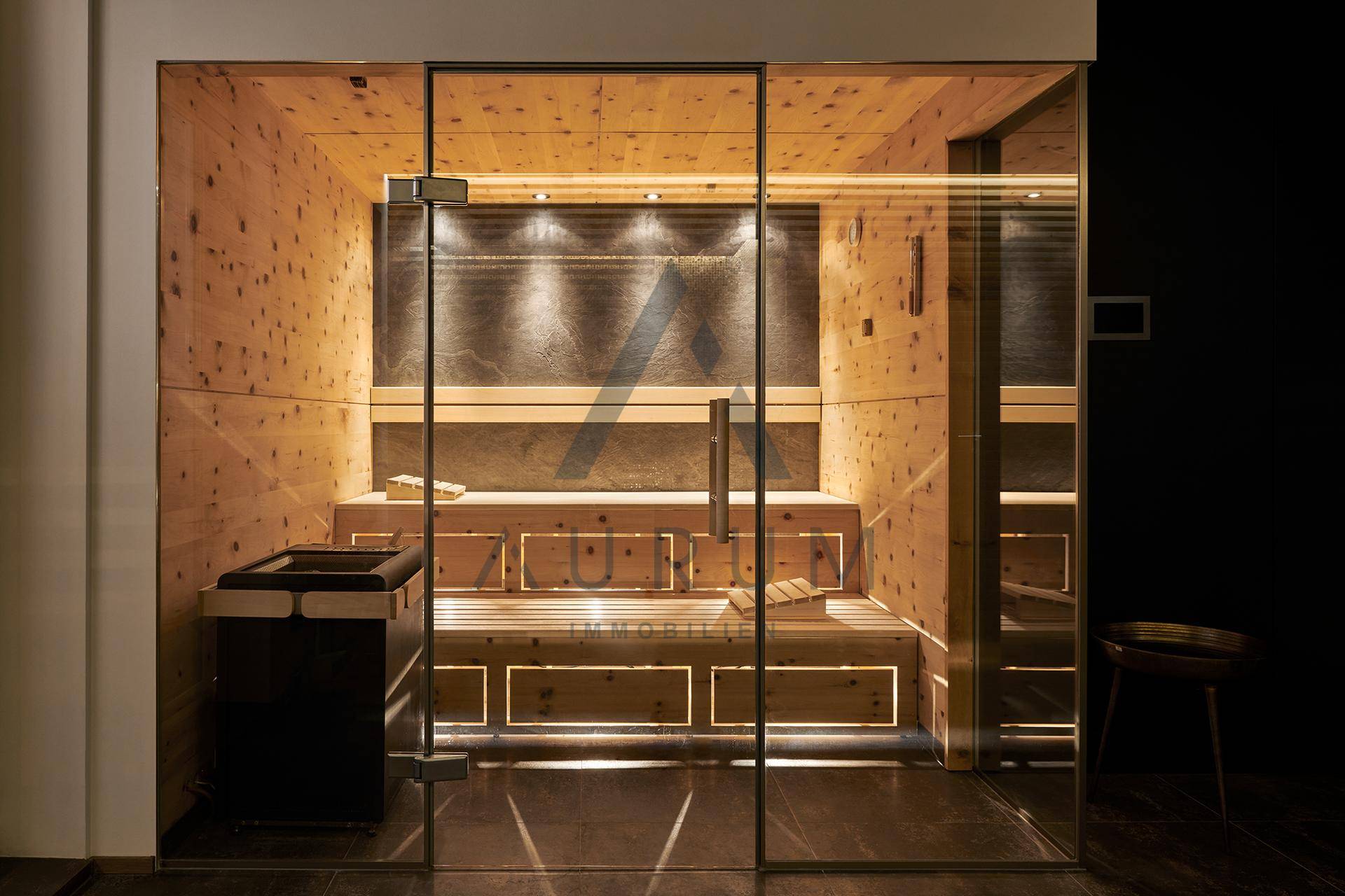 Moderne Sauna mit Holzverkleidung, Glasfront und indirekter Beleuchtung.
