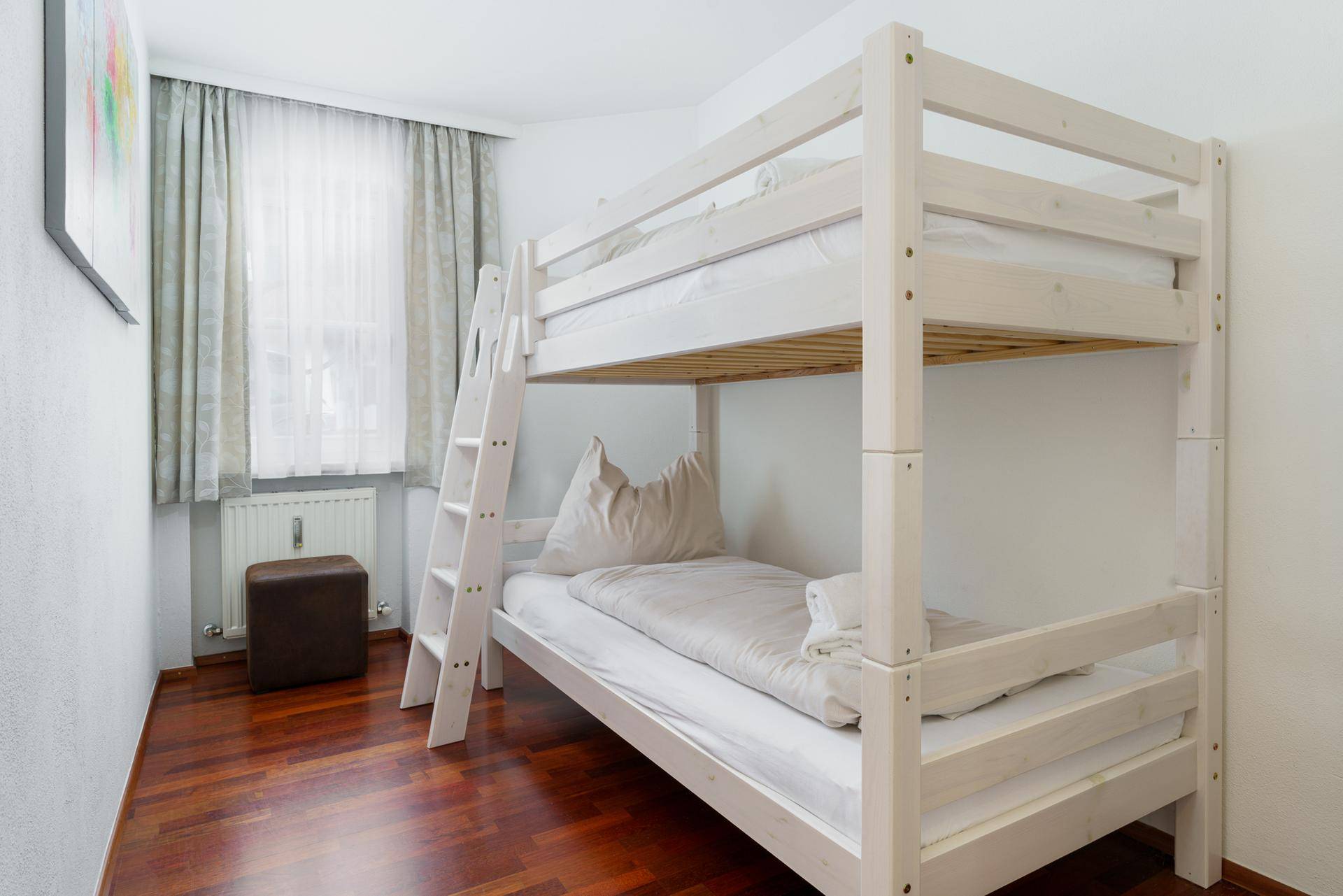 Kinderzimmer mit weißem Etagenbett und Holzboden, ideal für Gäste oder Familien.
