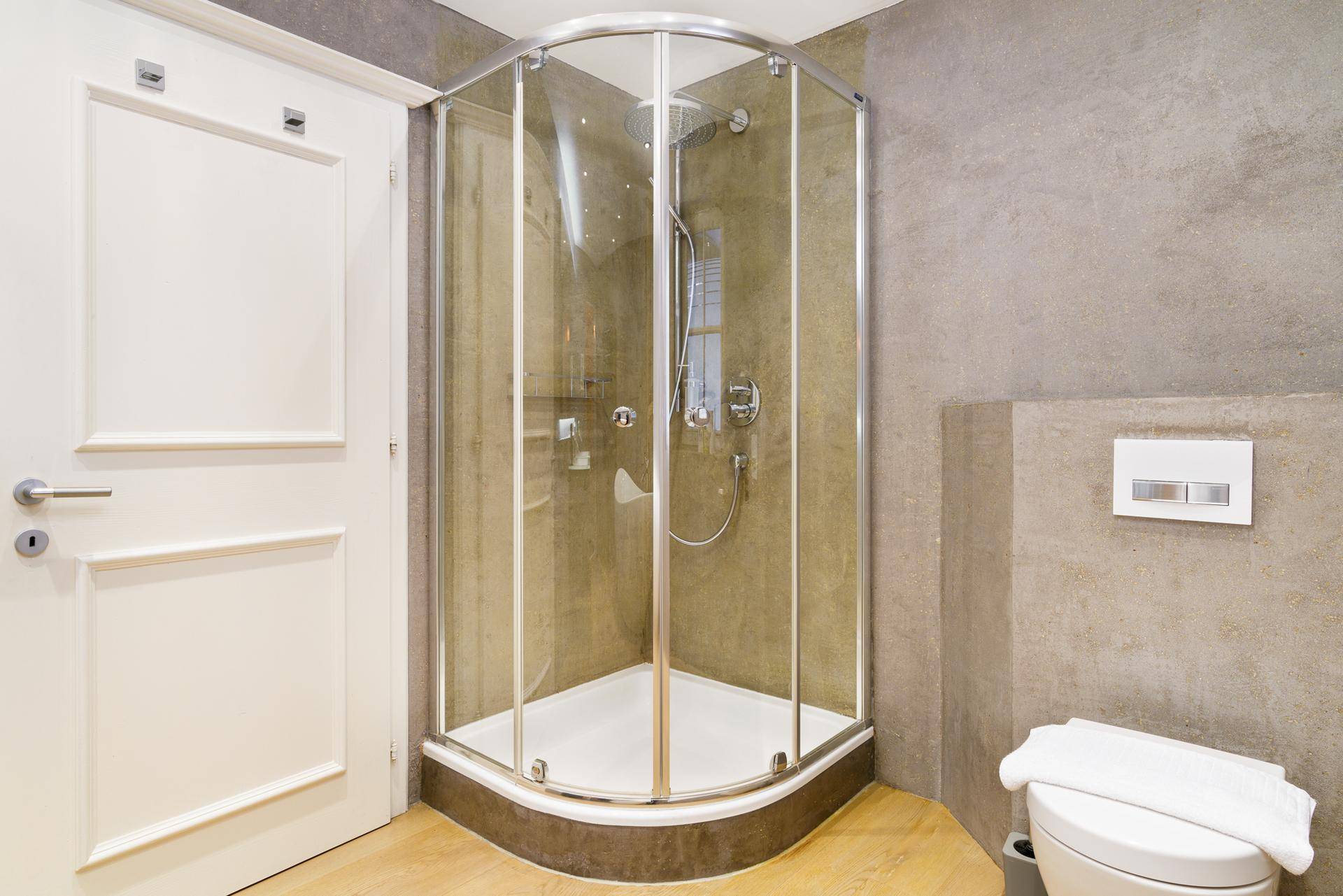 Badezimmer mit moderner Duschkabine und wandhängendem WC.