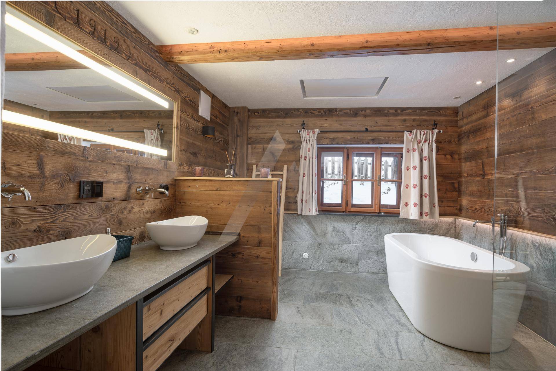 Luxuriöses Badezimmer mit freistehender Badewanne, Doppelwaschbecken und Holzwänden.