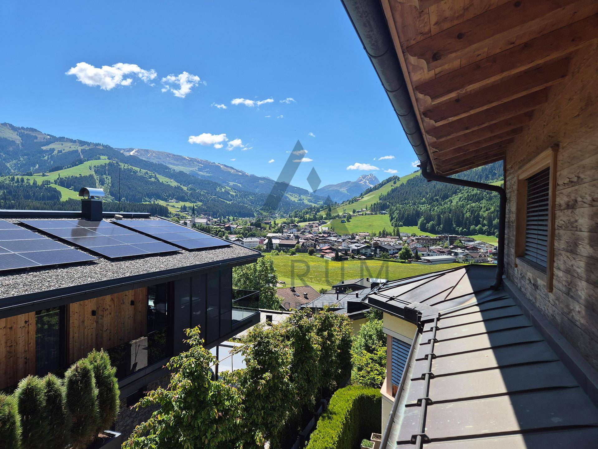 Blick auf ein Haus mit Photovoltaikanlage auf dem Dach und die malerische Berglandschaft im Hintergrund.