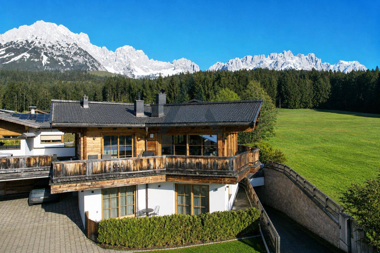 Traditionelles Chalet mit Holzbalkonen und beeindruckendem Bergblick in alpiner Landschaft.