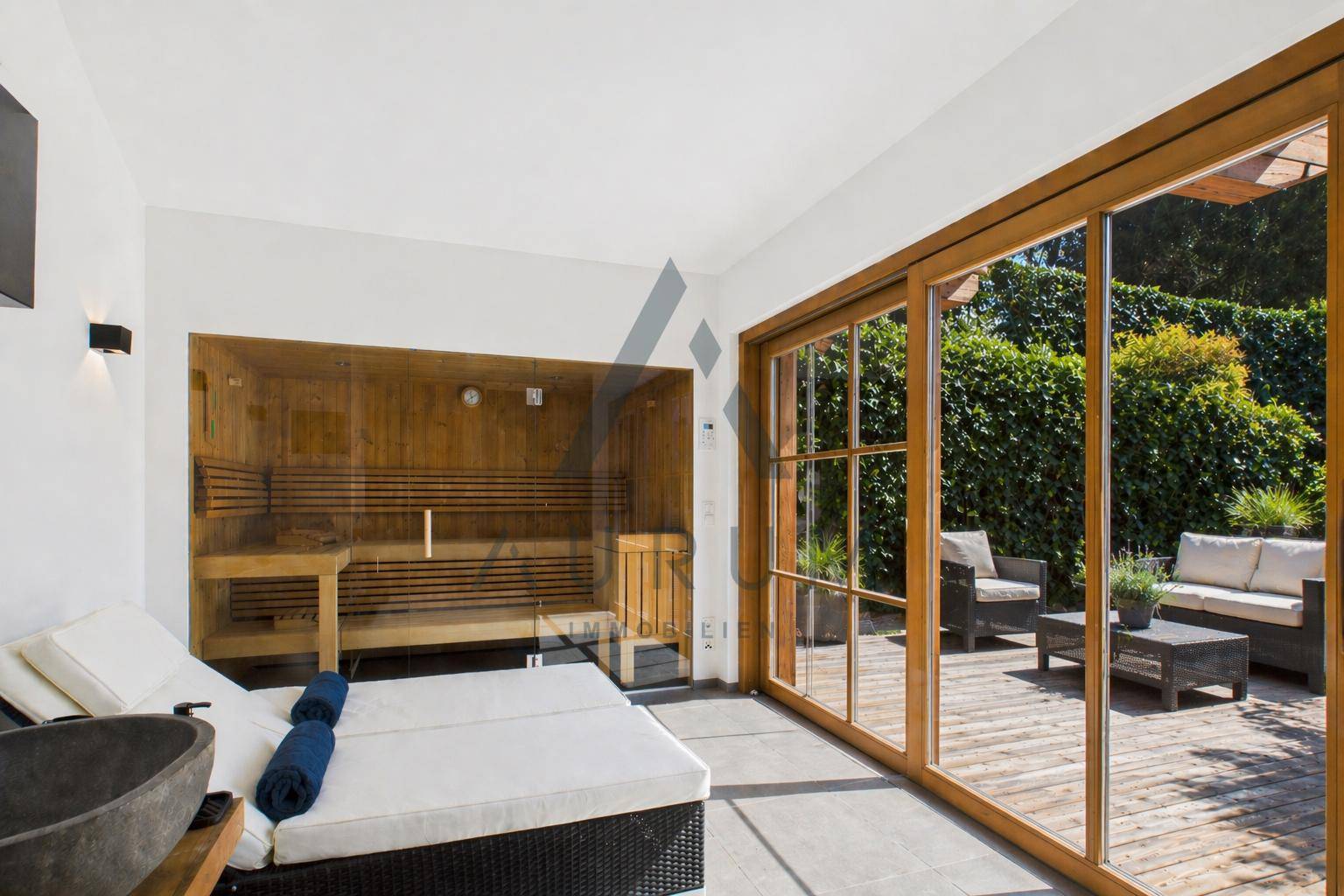 Wellnessbereich mit Sauna, Liegefläche und großen Glasschiebetüren zur Terrasse.