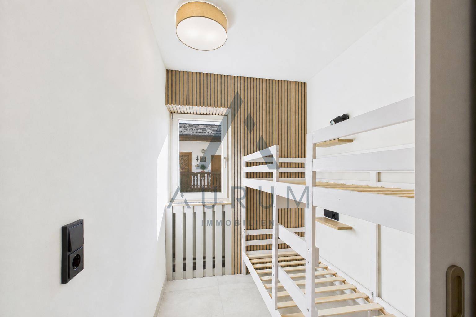 Kinderzimmer mit Etagenbetten, Holzvertäfelung und Fenster für natürliches Licht.