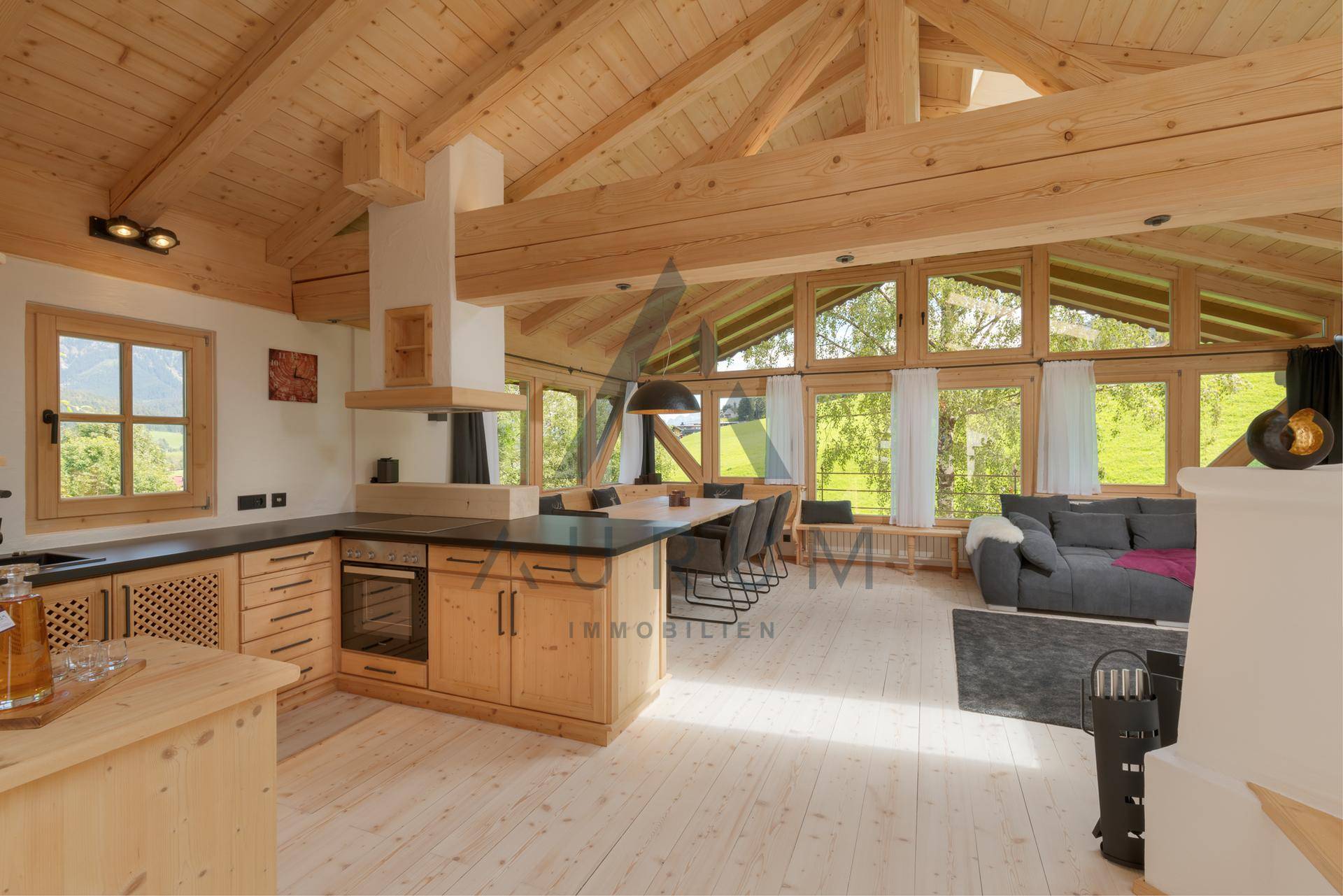 Heller, offener Wohnbereich mit Holzbalken, moderner Küche und Panoramablick auf die Berge.