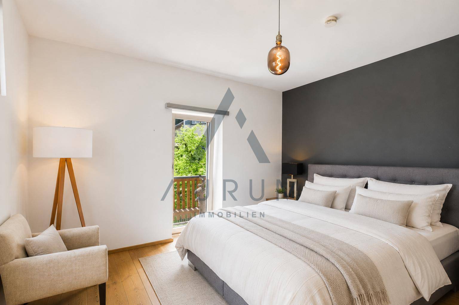 Elegantes Schlafzimmer mit dunkler Akzentwand, Doppelbett und Zugang zu einem Balkon.