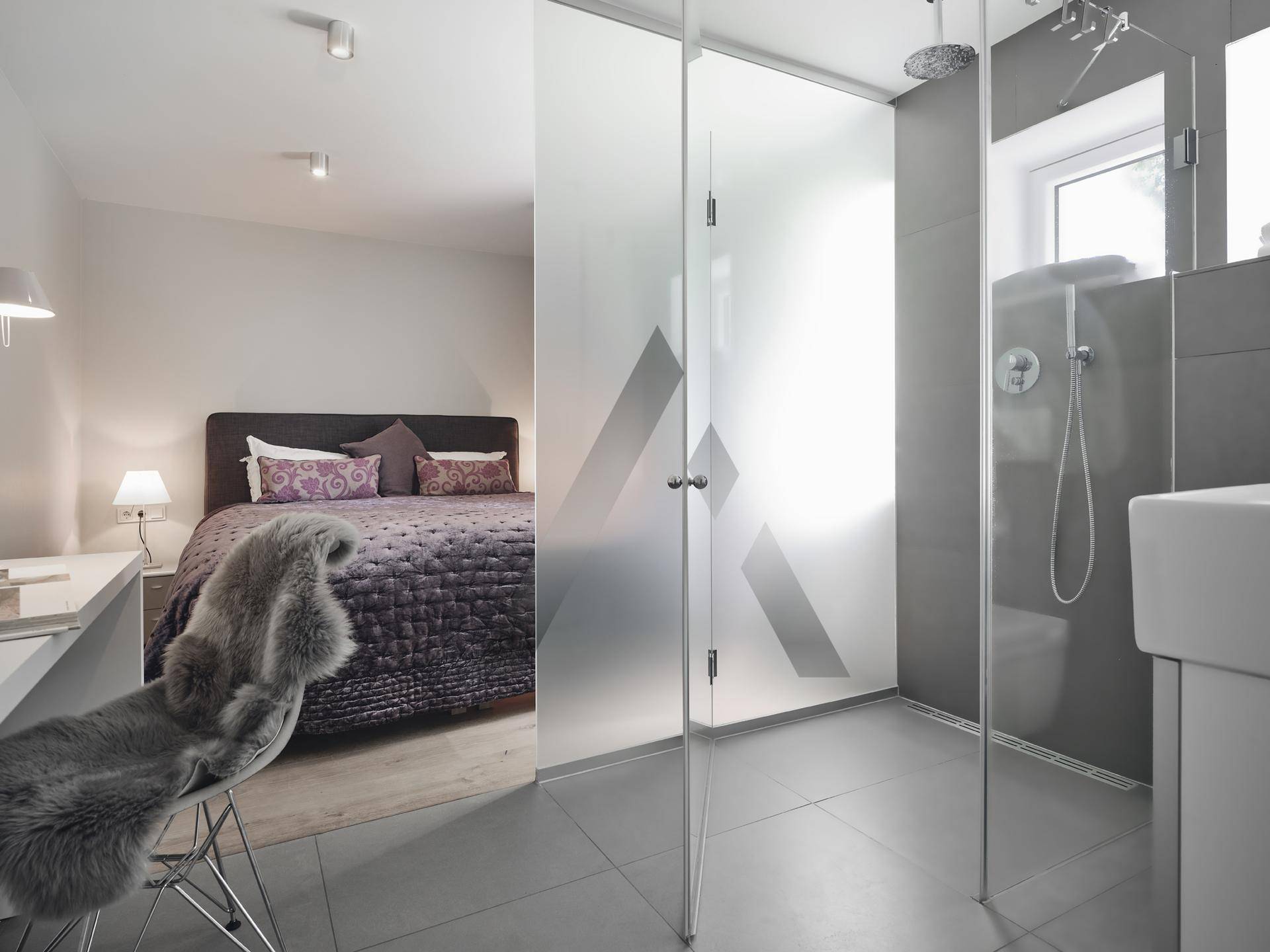 Schlafzimmer mit integriertem Duschbereich, modernen Fliesen und minimalistischem Design.