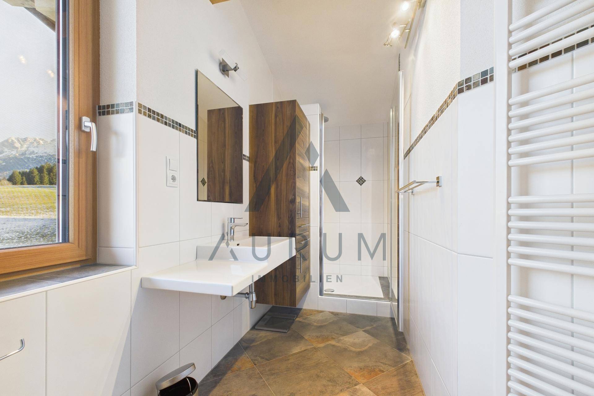 Helles Badezimmer mit Dusche, modernem Waschtisch und Fenster mit Blick ins Grüne.