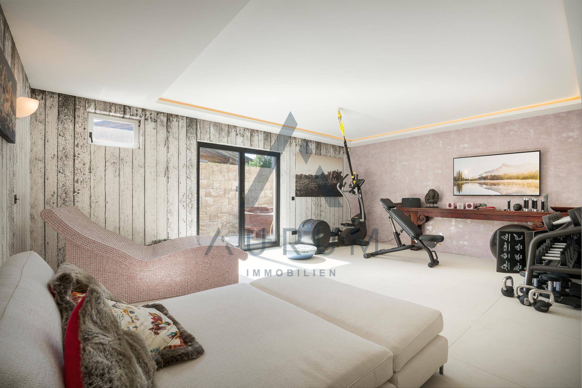Privater Fitnessraum mit verschiedenen Trainingsgeräten und Zugang zu einem Außenbereich.