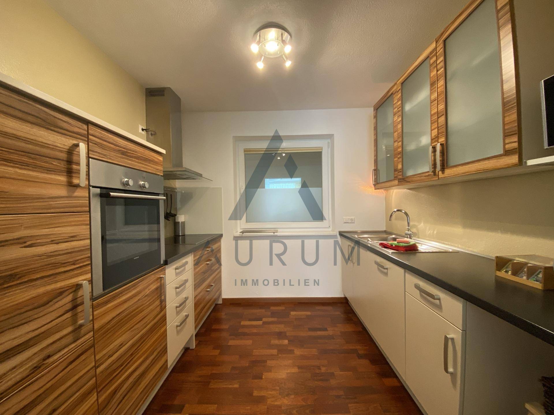 Funktionale Küche mit Holz- und weißen Schränken, Einbaugeräten und Fenster.