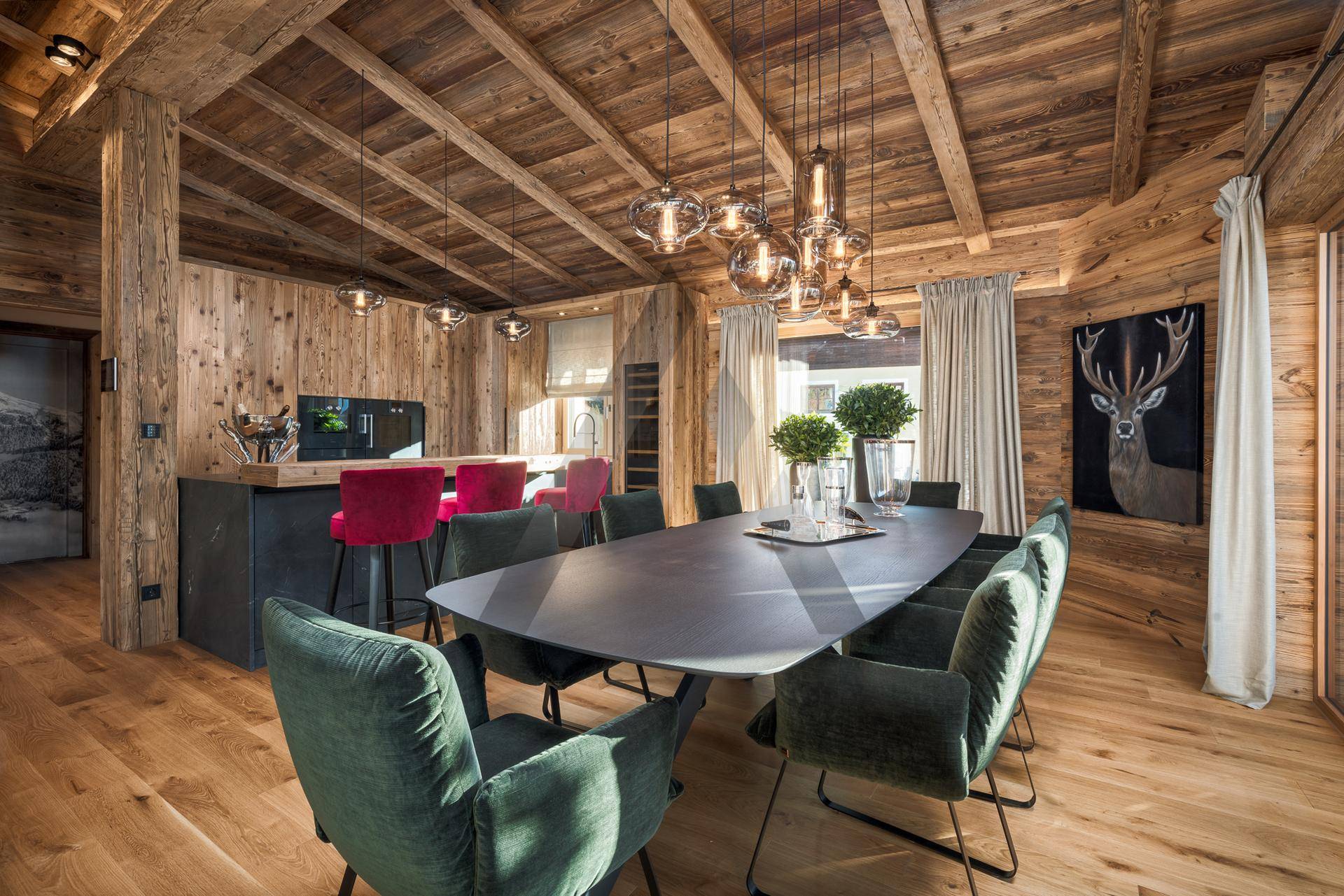Eleganter Essbereich mit modernem Tisch, Samtstühlen und Holzwänden, angrenzend an eine Küchenzeile.