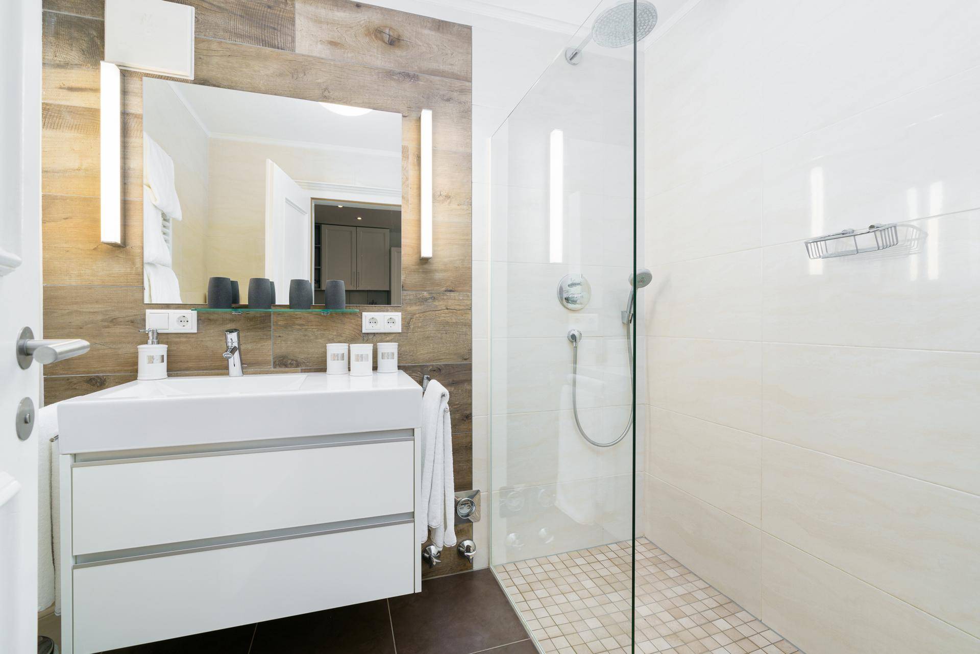 Modernes Badezimmer mit begehbarer Dusche, stilvollem Waschtisch und Holzoptik-Wandverkleidung.