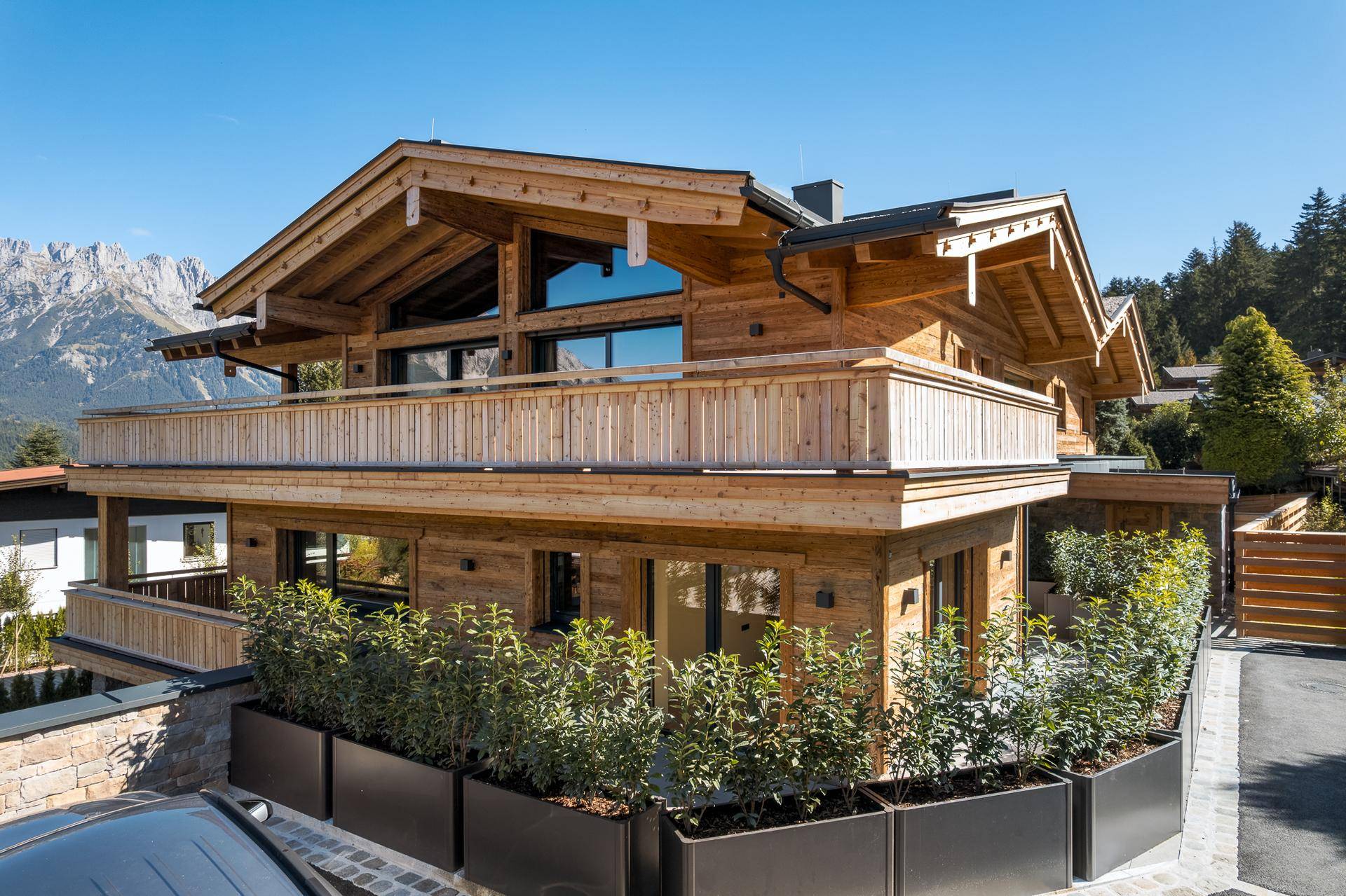 Elegantes Holzchalet mit traditioneller Architektur und Balkonen, umgeben von alpiner Landschaft.