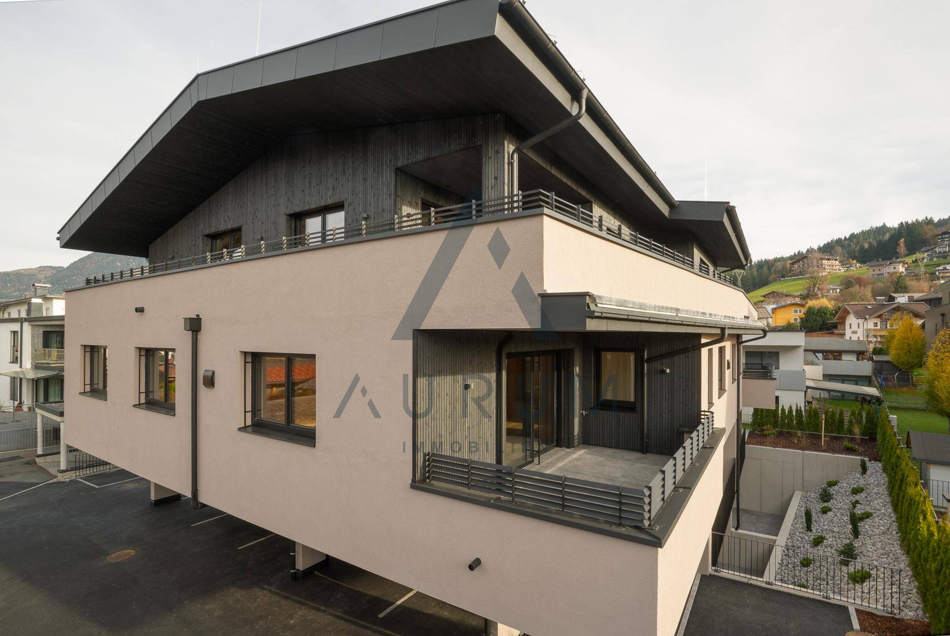 Moderne Wohnanlage mit mehreren Balkonen und Terrassen in alpiner Umgebung.