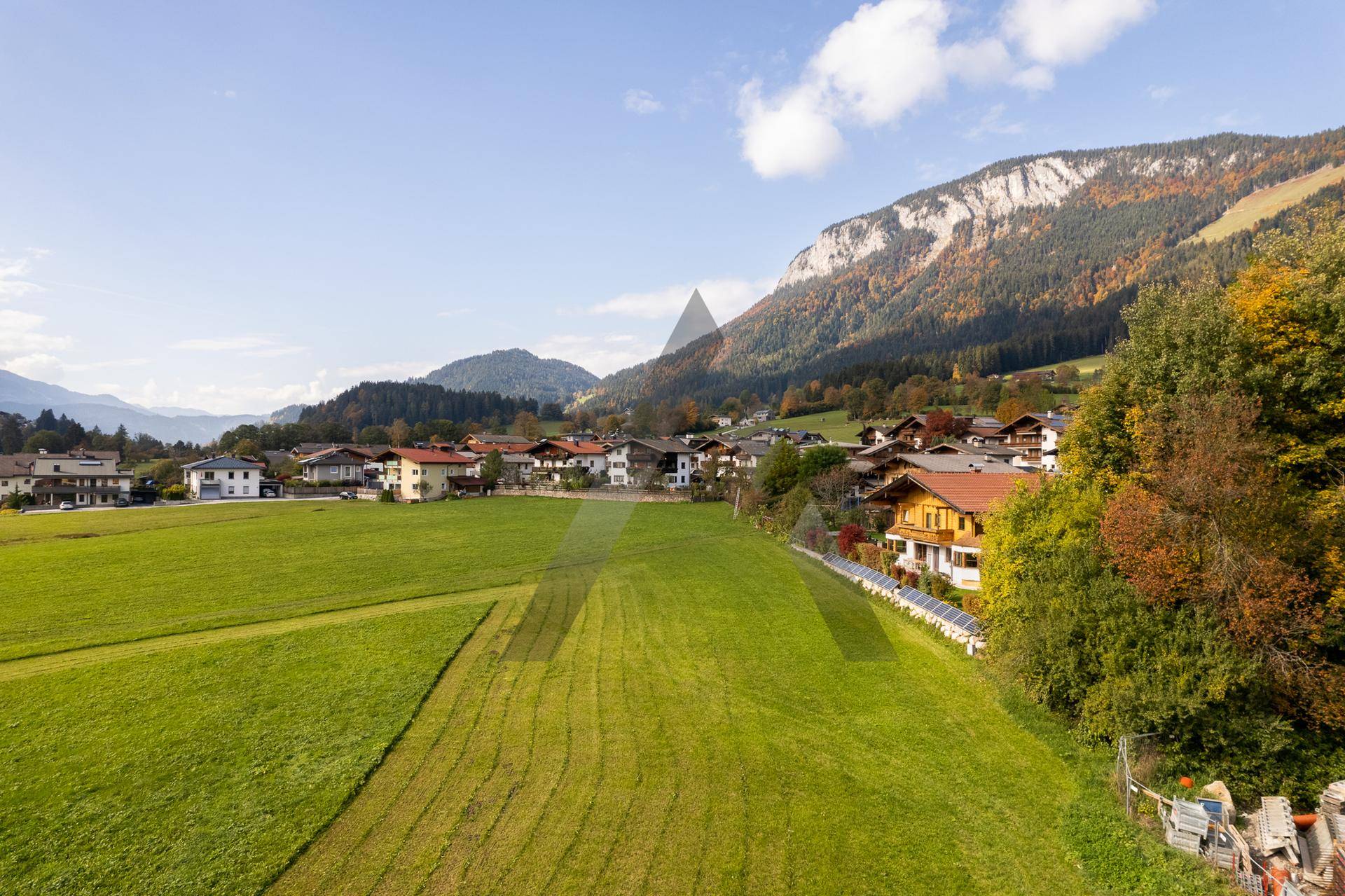 Panoramablick auf ein malerisches Dorf in den Bergen mit grünen Wiesen im Vordergrund.