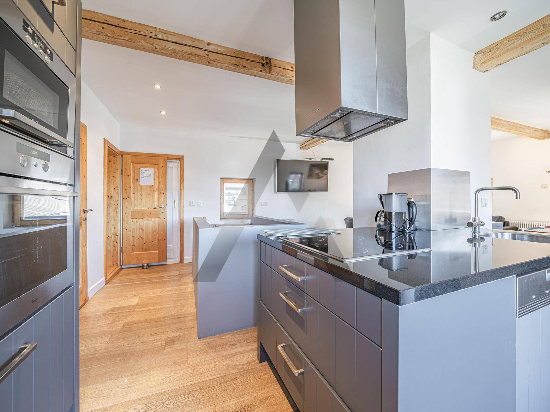 Moderne Küche mit dunklen Schränken, Kochinsel und integrierten Geräten in offenem Design.