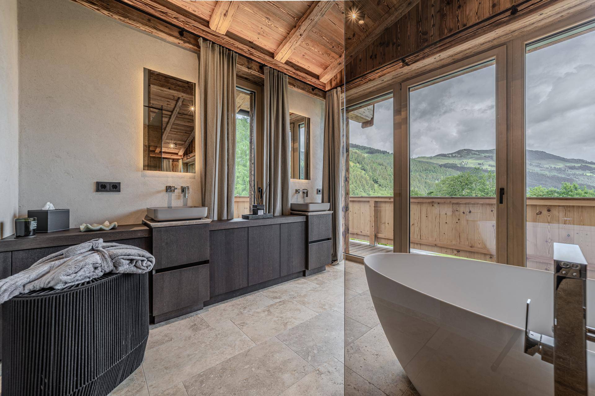 Elegantes Badezimmer mit freistehender Badewanne, Doppelwaschbecken und Balkonzugang mit Bergblick.