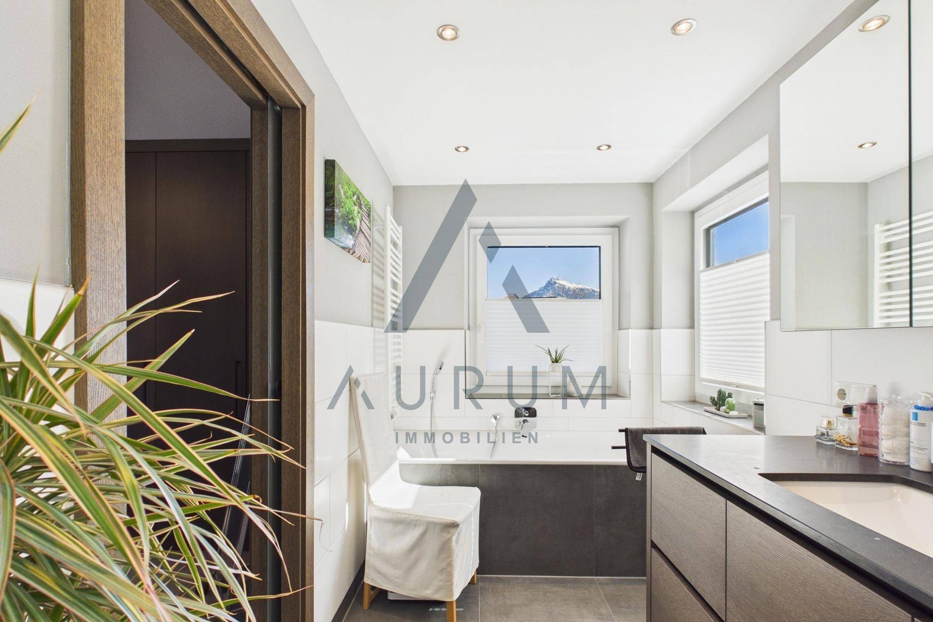 Helles Badezimmer mit Badewanne, Waschtisch und Fenster mit Bergblick.