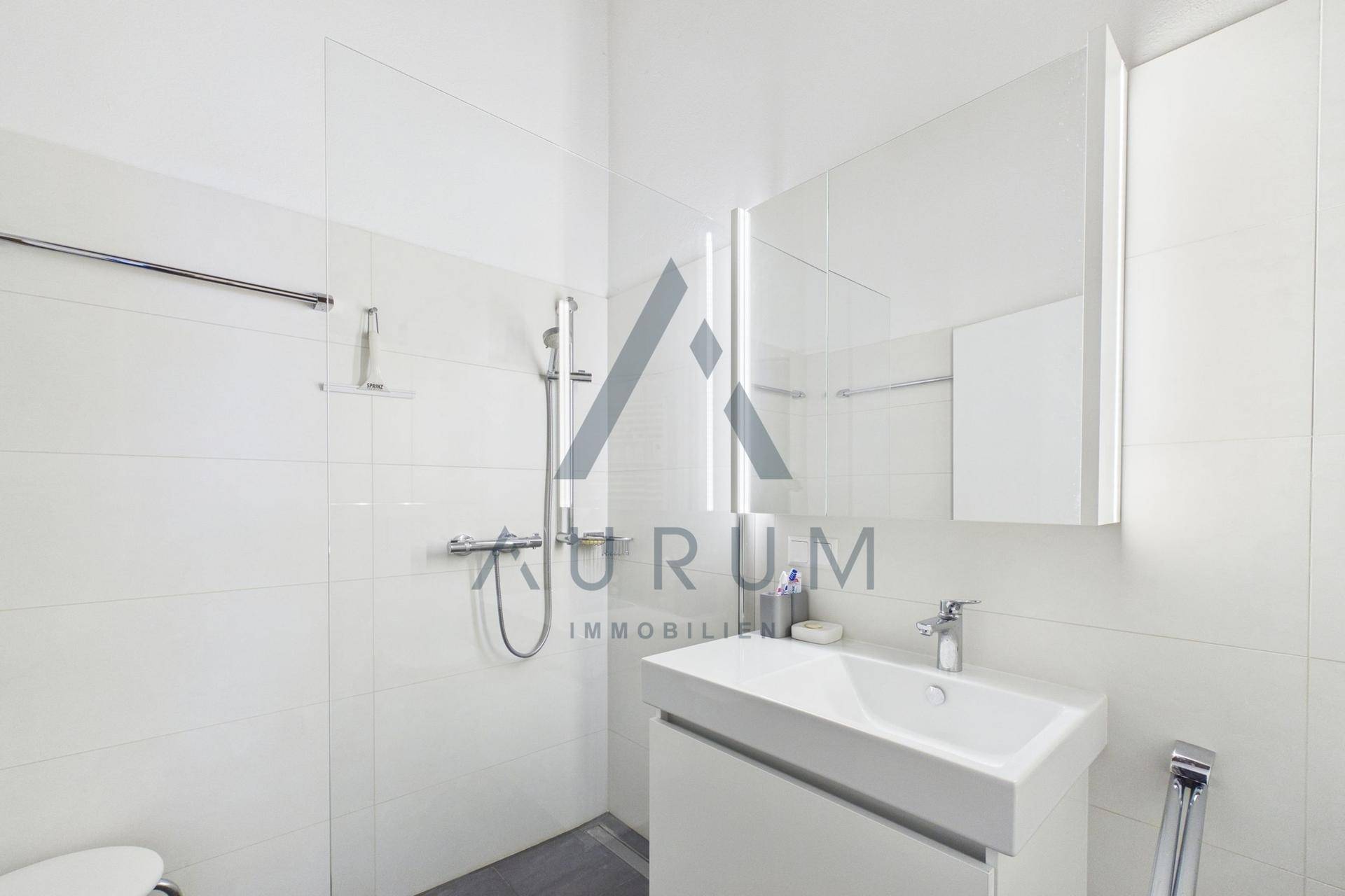 Modernes Badezimmer mit Dusche, Waschbecken und weißer Fliesenverkleidung.