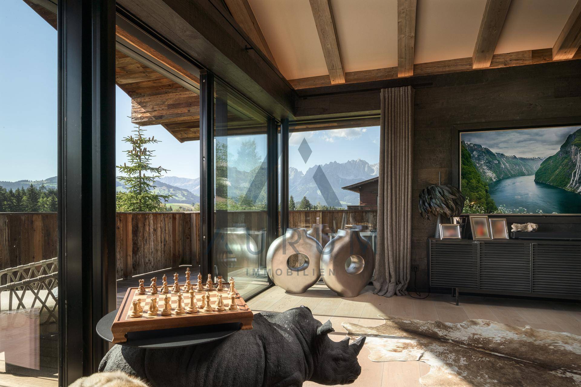 Heller Wohnbereich mit großen Glasfronten, die einen atemberaubenden Blick auf die Berge bieten.