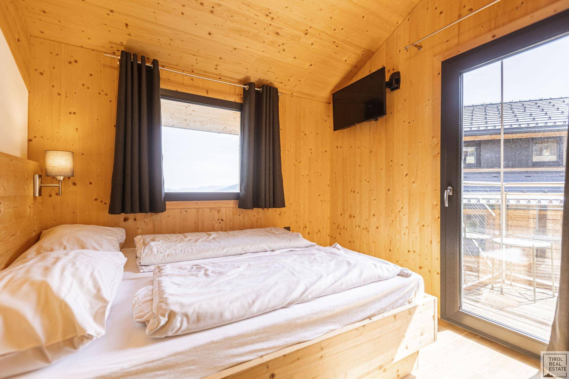Helles Schlafzimmer mit Holzeinrichtung, Doppelbett und Blick nach draußen.