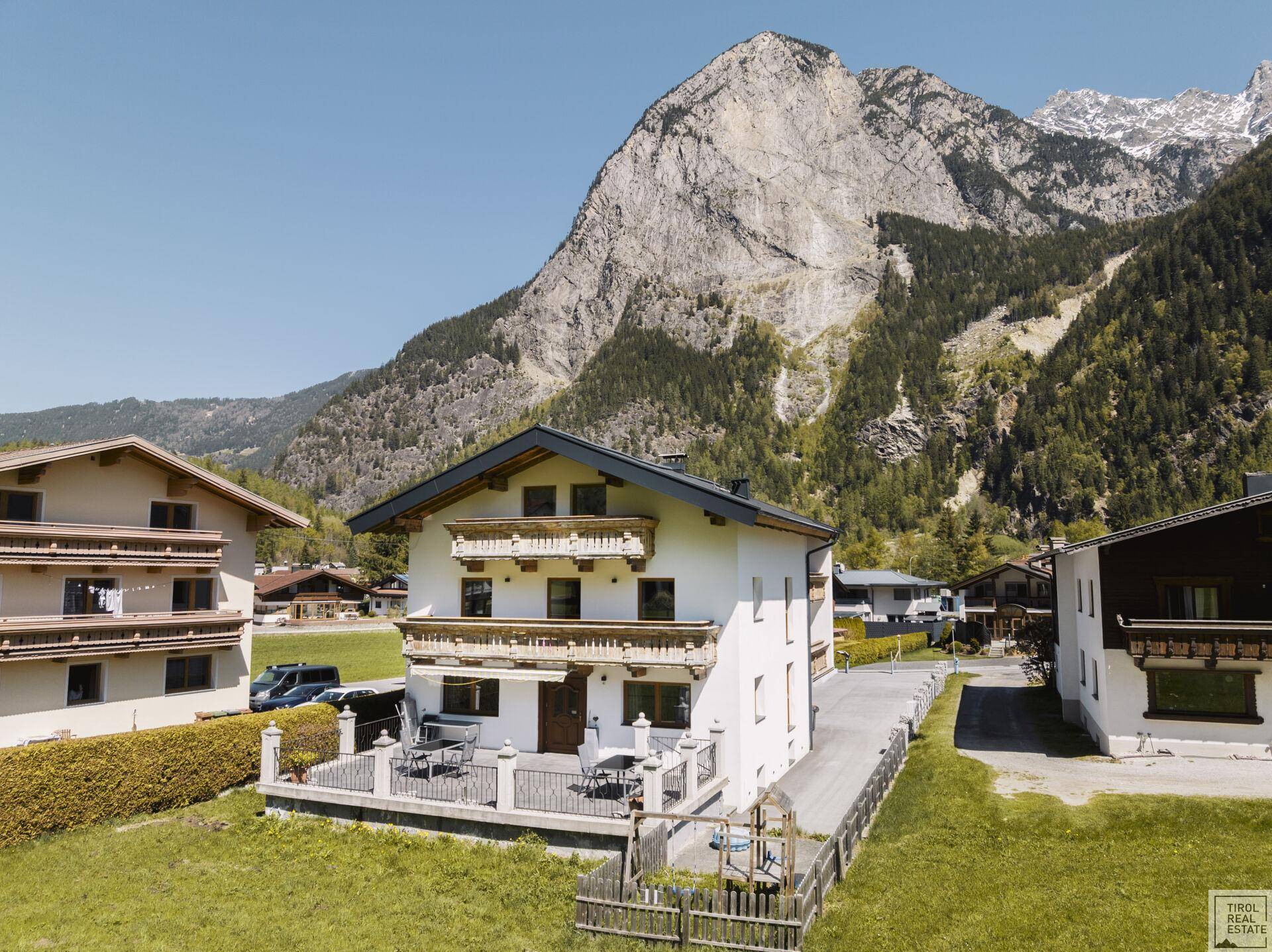 Traditionelles Wohnhaus in alpiner Umgebung mit großem Garten und beeindruckendem Bergblick.