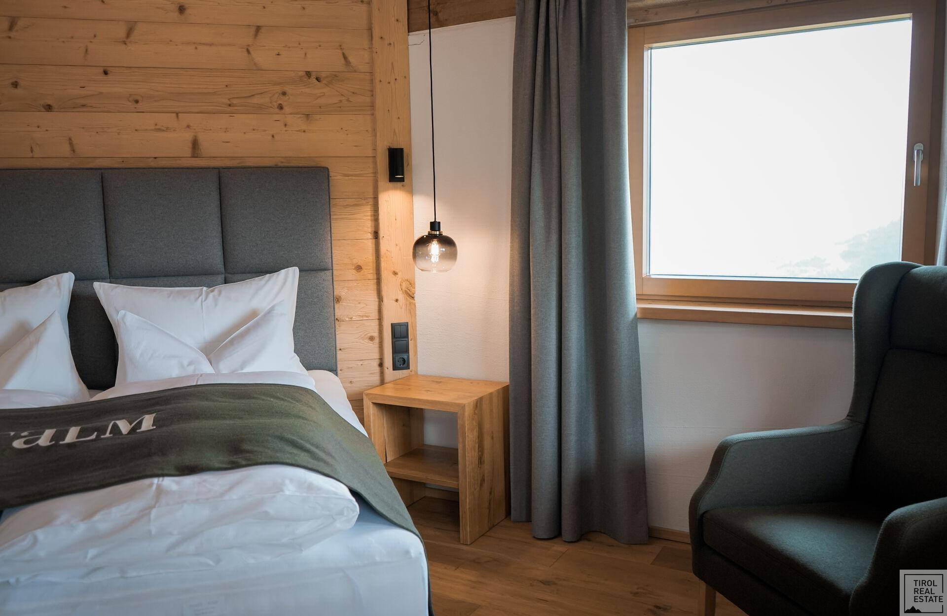 Gemütliches Schlafzimmer mit Holzwänden, bequemen Bett und Fenster für natürliches Licht.